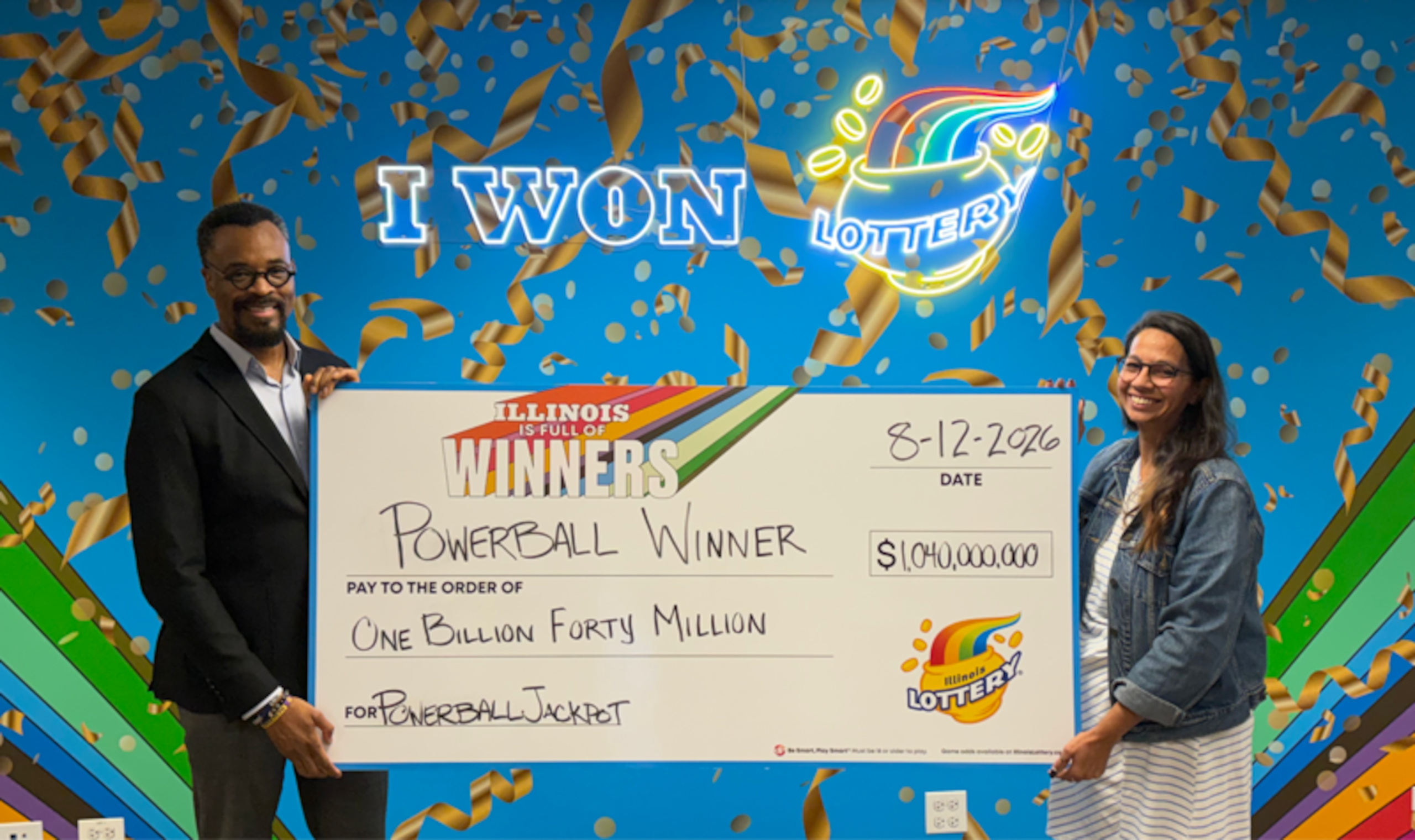 El director de la Lotería de Illinois, Harold Mays, y la gerente del Centro de Premios de Chicago, Amanda Crosas, sostienen el cheque que representa el premio de $1,040 millones del Powerball.
