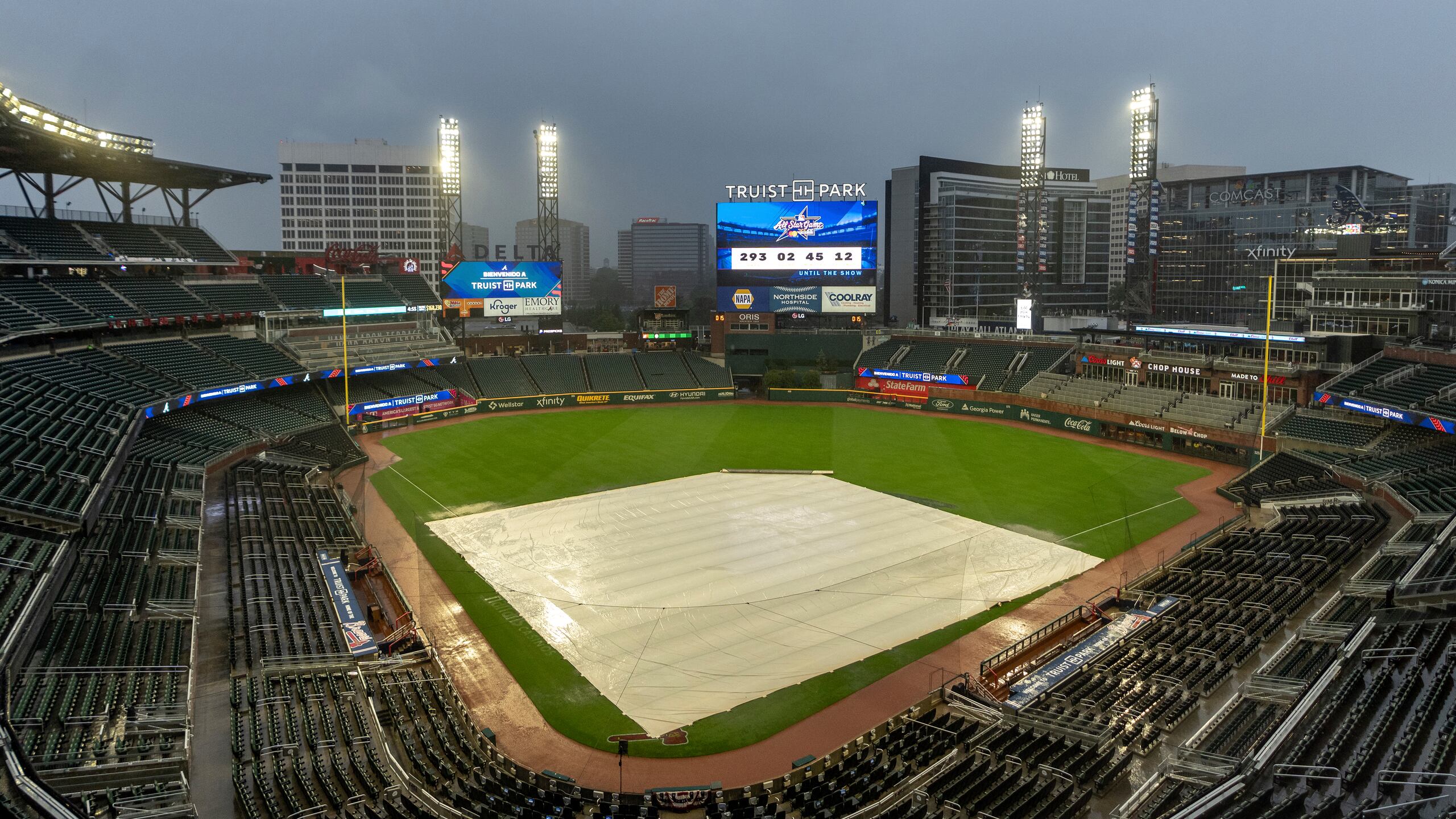 Una lona cubre el cuadro mientras cae la lluvia en Truist Park después de que el juego de béisbol entre los New York Mets y los Atlanta Braves fuera pospuesto.