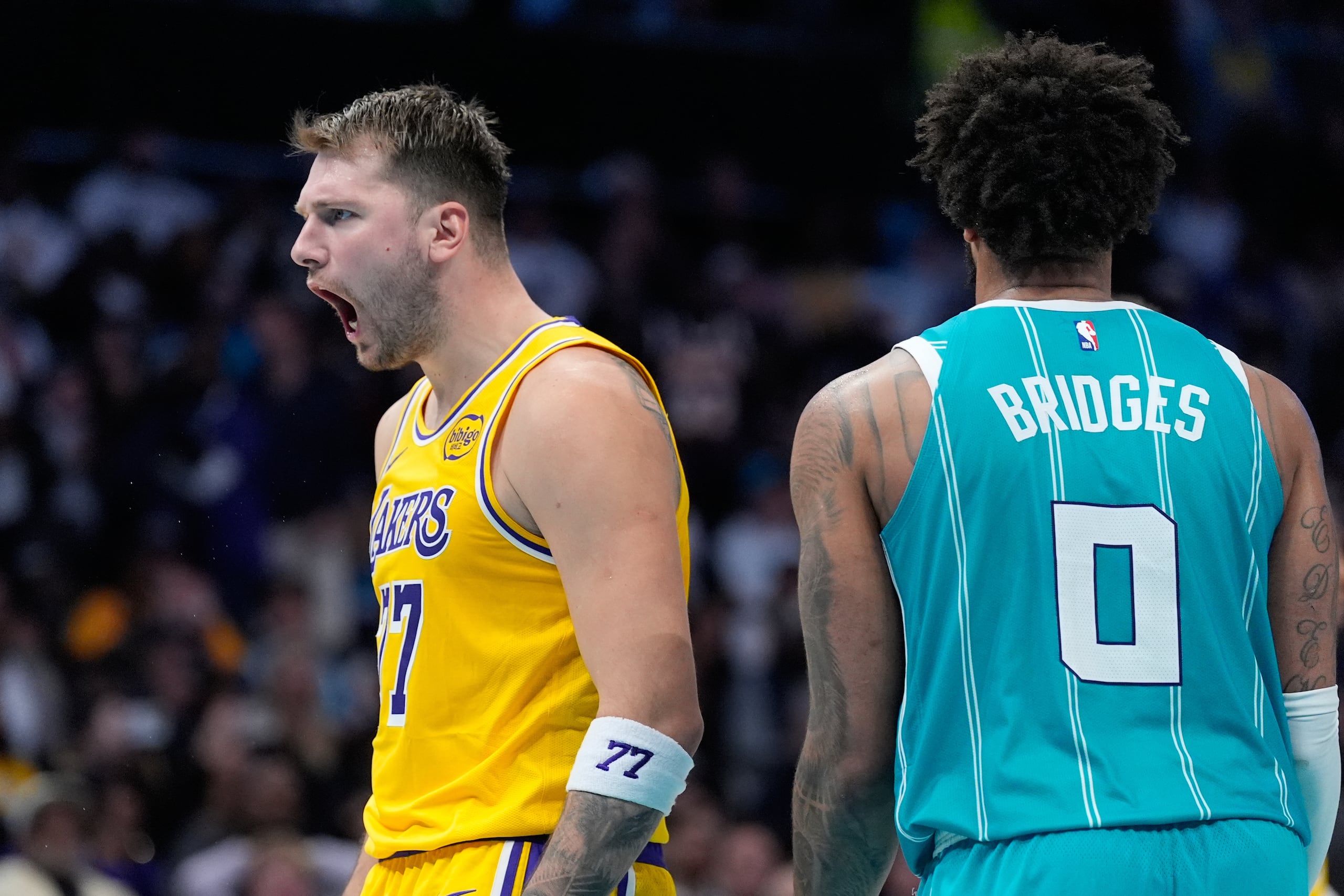 Luka Doncic, de los Lakers de Los Ángeles, celebra después de encestar mientras Miles Bridges, de los Hornets de Charlotte, observa durante la segunda mitad del juego de baloncesto de la NBA, el lunes 10 de noviembre de 2025, en Charlotte, Carolina del Norte. (AP Foto/Chris Carlson)