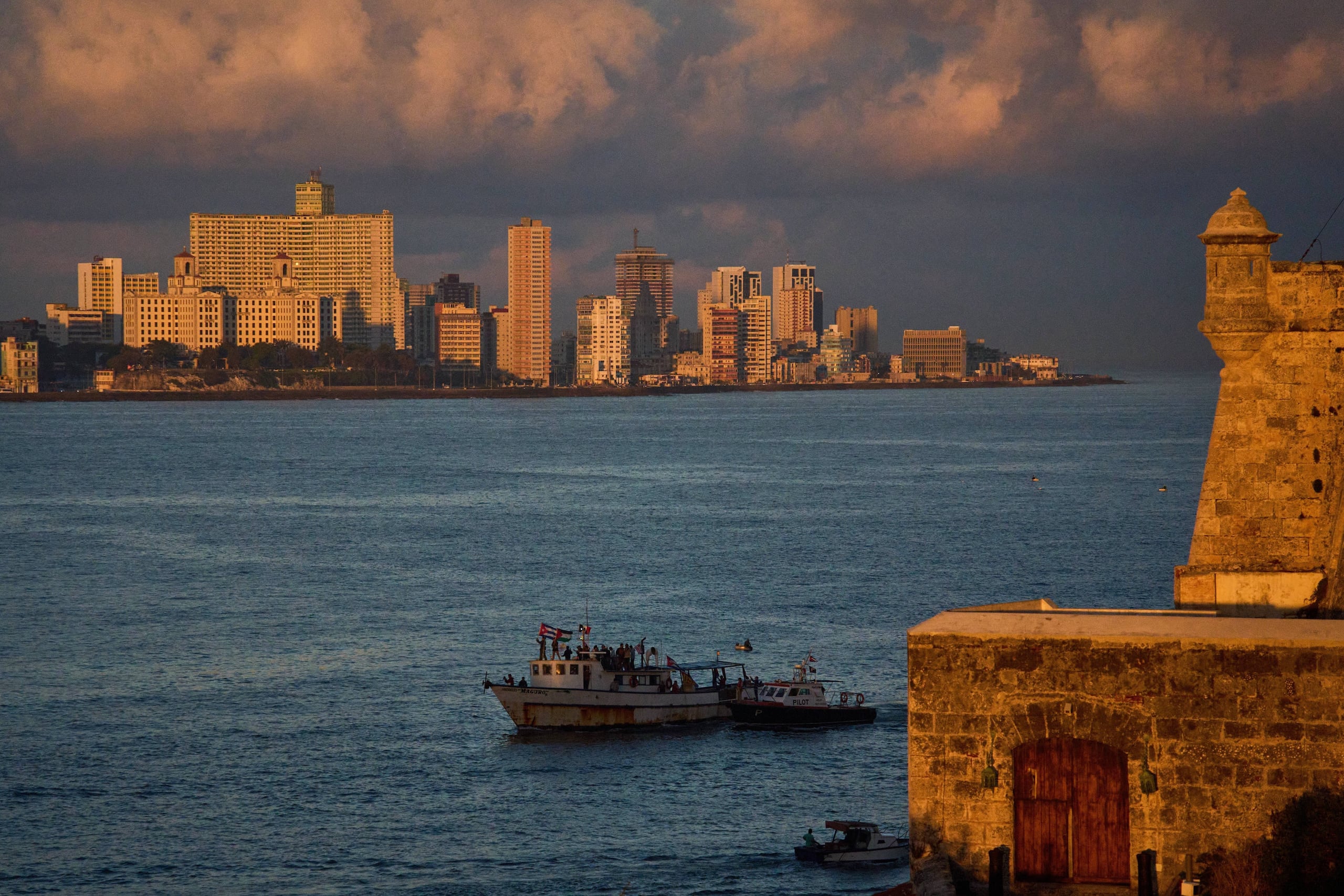 Activistas ondean banderas cubanas y palestinas desde el buque Maguro, que llega procedente de México con ayuda humanitaria como parte del convoy "Nuestra América", en la bahía de La Habana, Cuba, el martes 24 de marzo de 2026. (AP Foto/Ramón Espinosa)