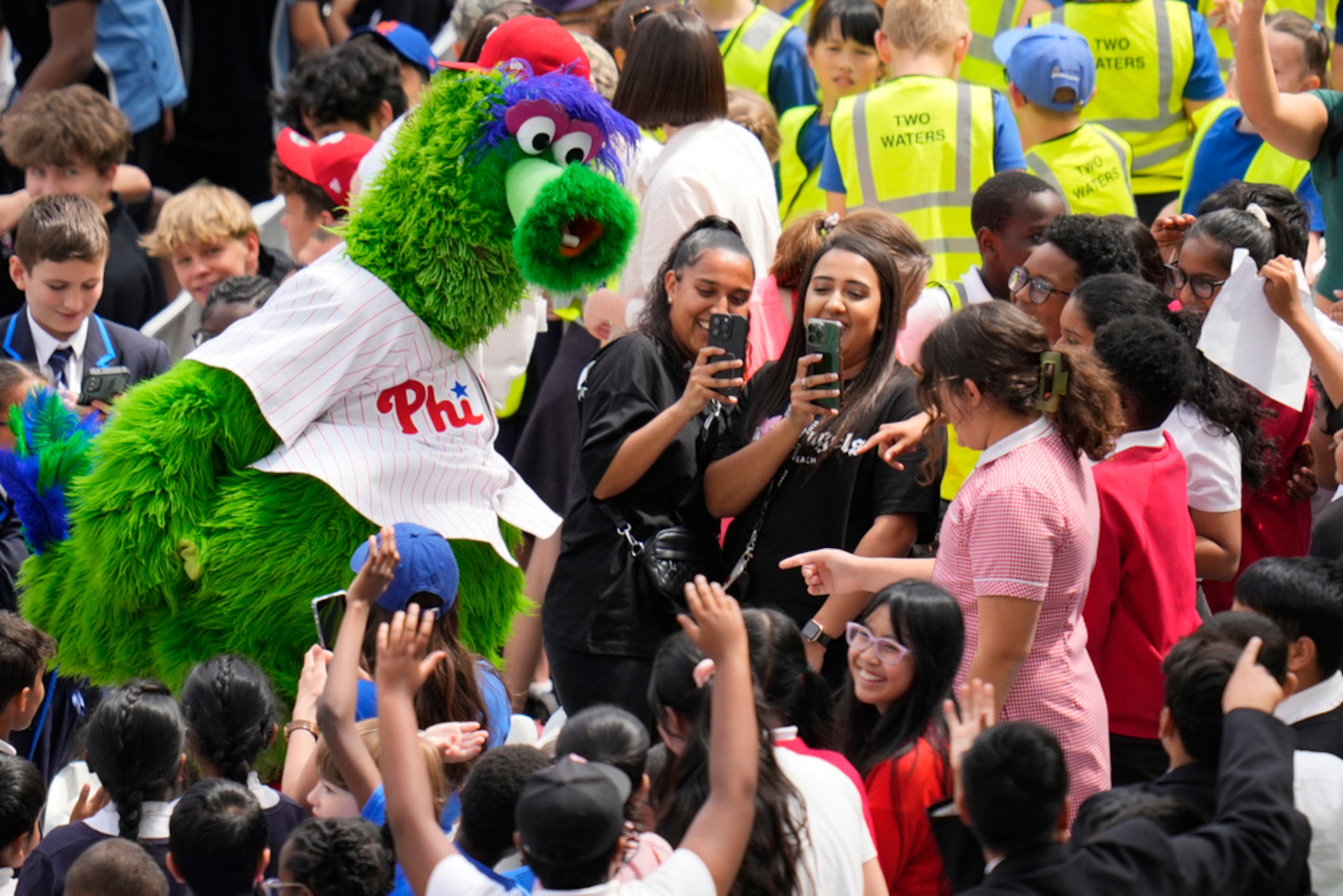 El Phillie Phanatic interactúa con estudiantes durante una práctica del equipo en London Stadium.