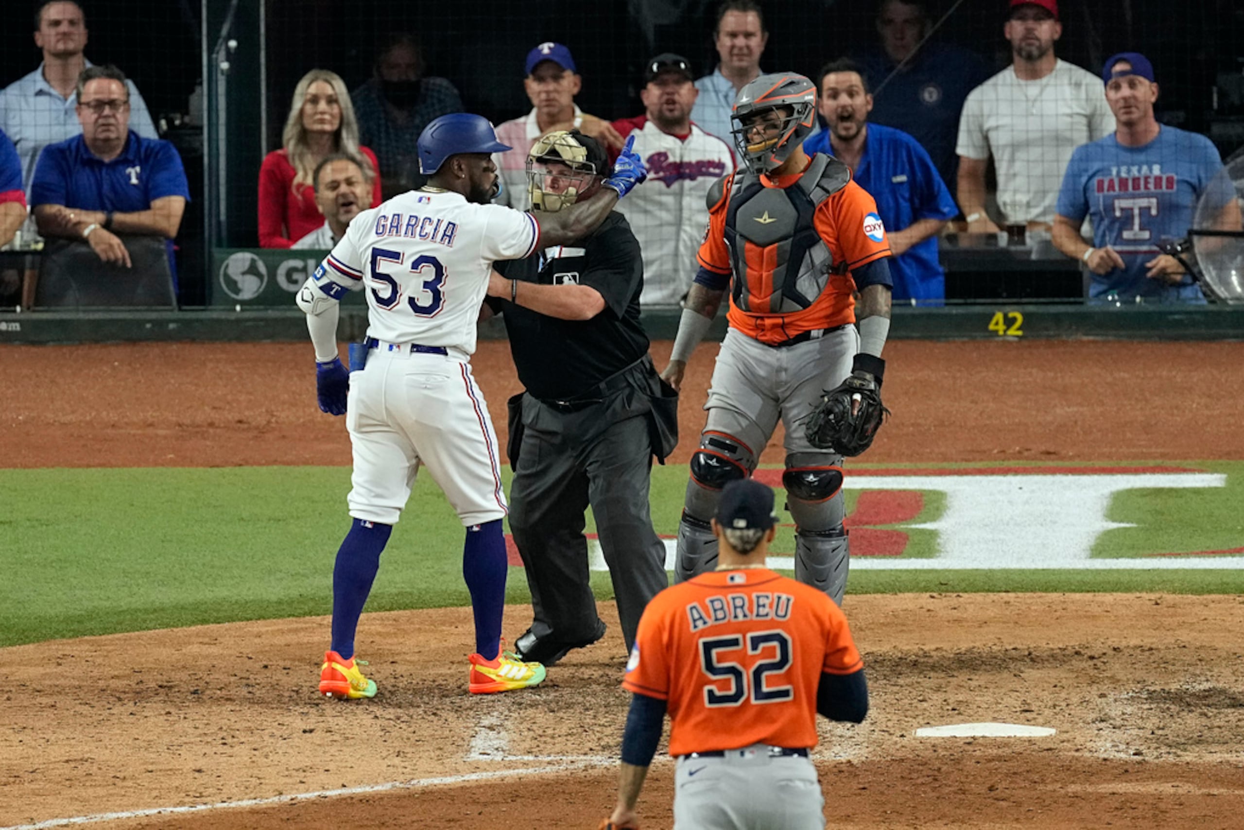 Adolis García es contenido por el árbitro Marvin Hudson mientras le reclama al boricua Martín Maldonado después de recibir un pelotazo de Bryan Abreu.
