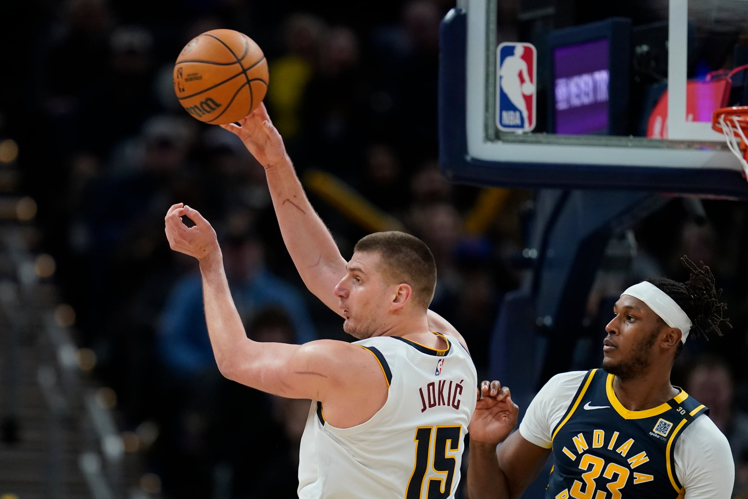 Nikola Jokic, de los Nuggets de Denver, realiza un pase frente a Myles Turner, de los Pacers de Indiana.