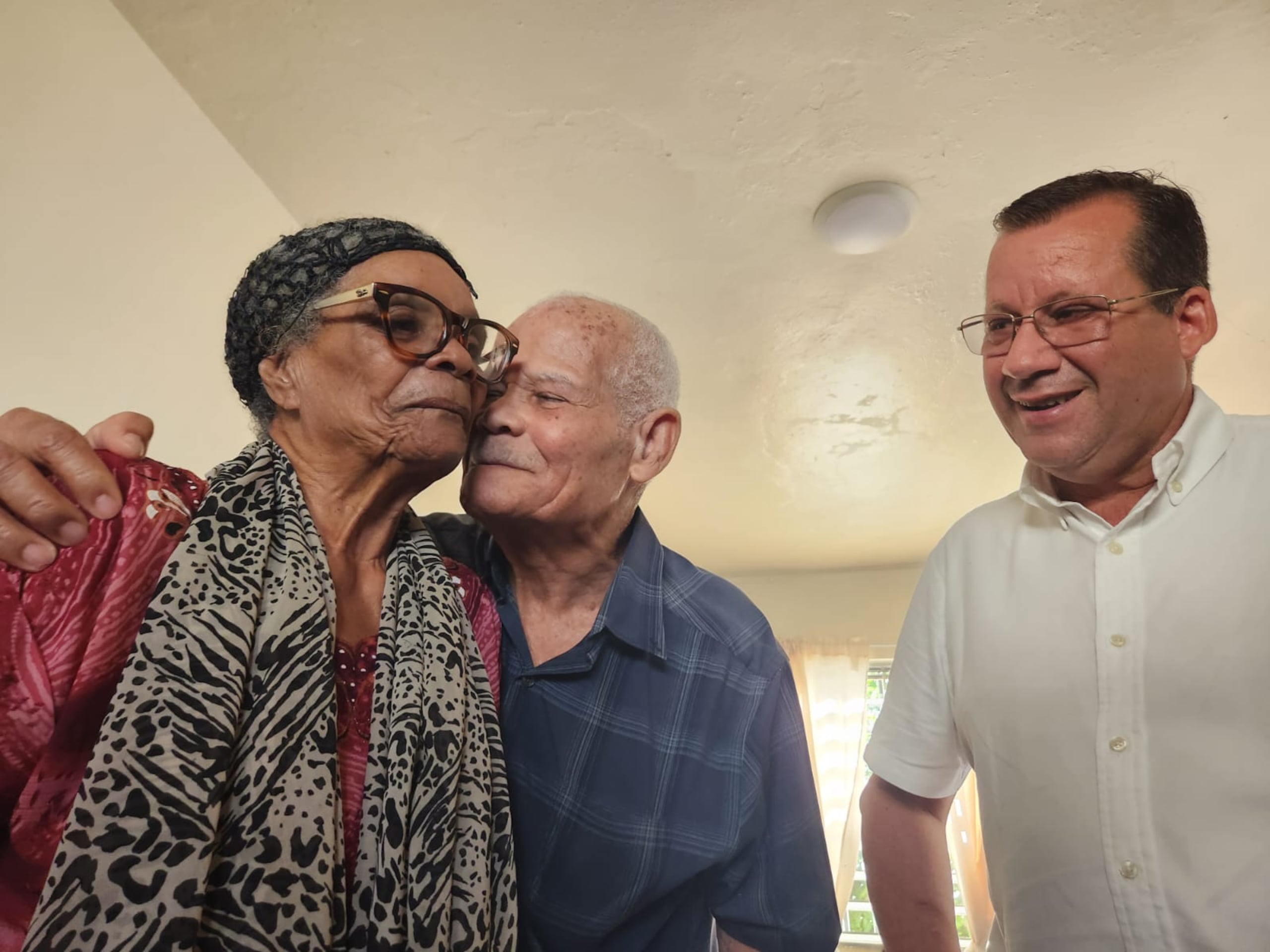 Carmen Catalá Benítez y Eduardo Valcárcel se abrazan ante la mirada del alcalde, Edward O'Neill.