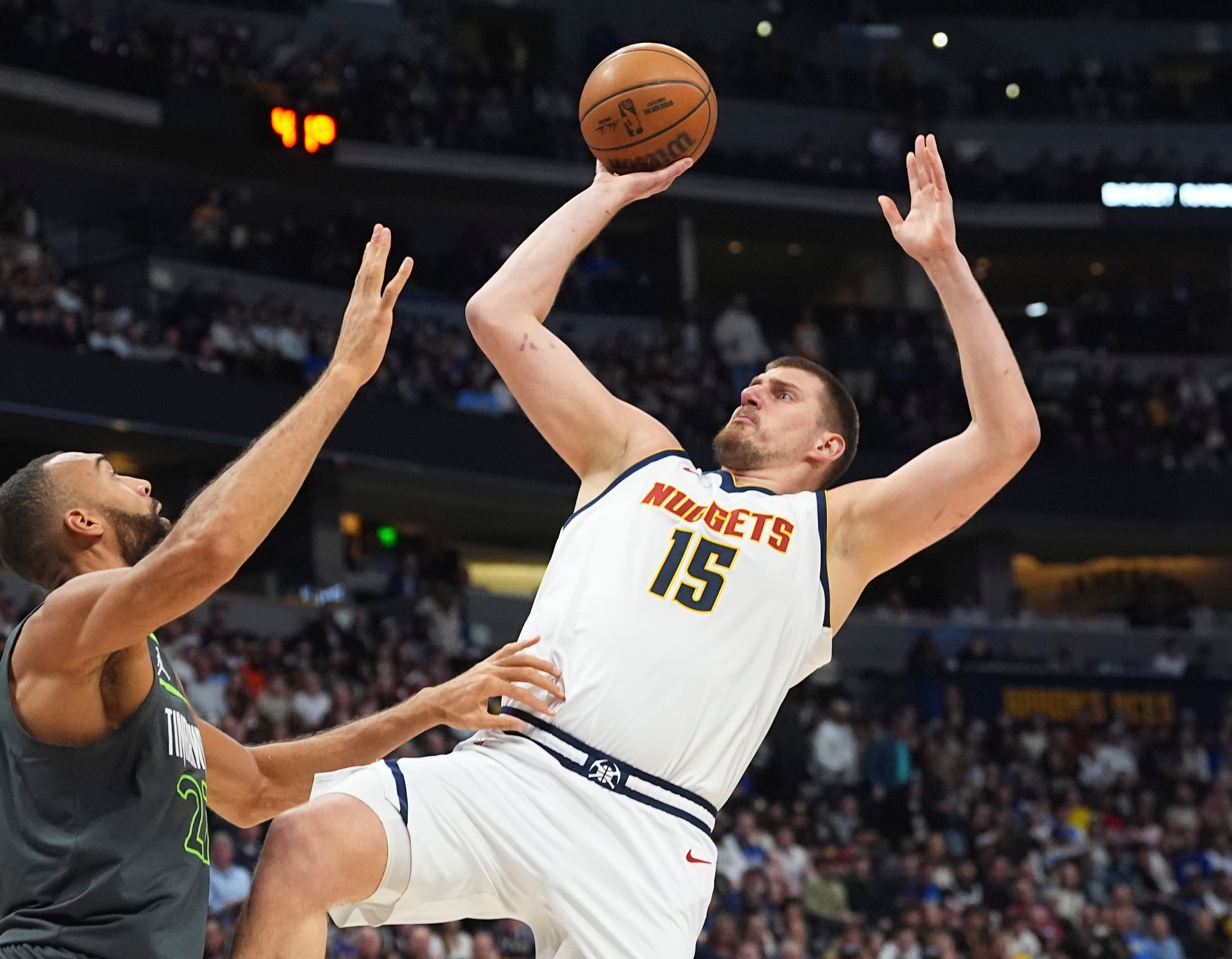 Nikola Jokic, de los Nuggets de Denver, lanza frente a Rudy Gobert, de los Timberwolves de Minnesota.