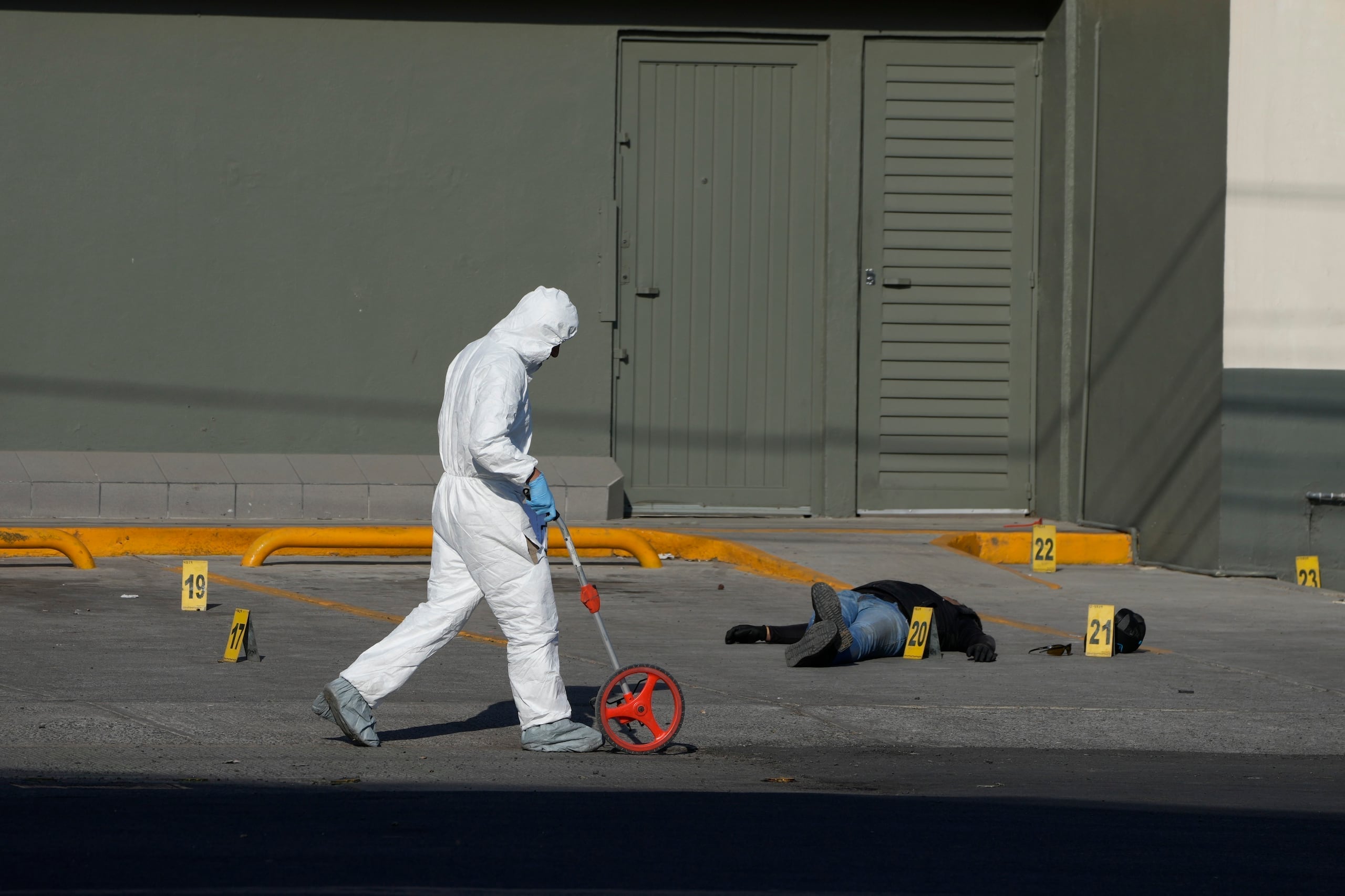 Un investigador policial recopila evidencias en el escenario de un crimen donde yace el cadáver de una persona identificada por la policía como un atacante implicado en el tiroteo letal de un agente, en Celaya, México, el 28 de febrero de 2024. (AP Foto/Fernando Llano)