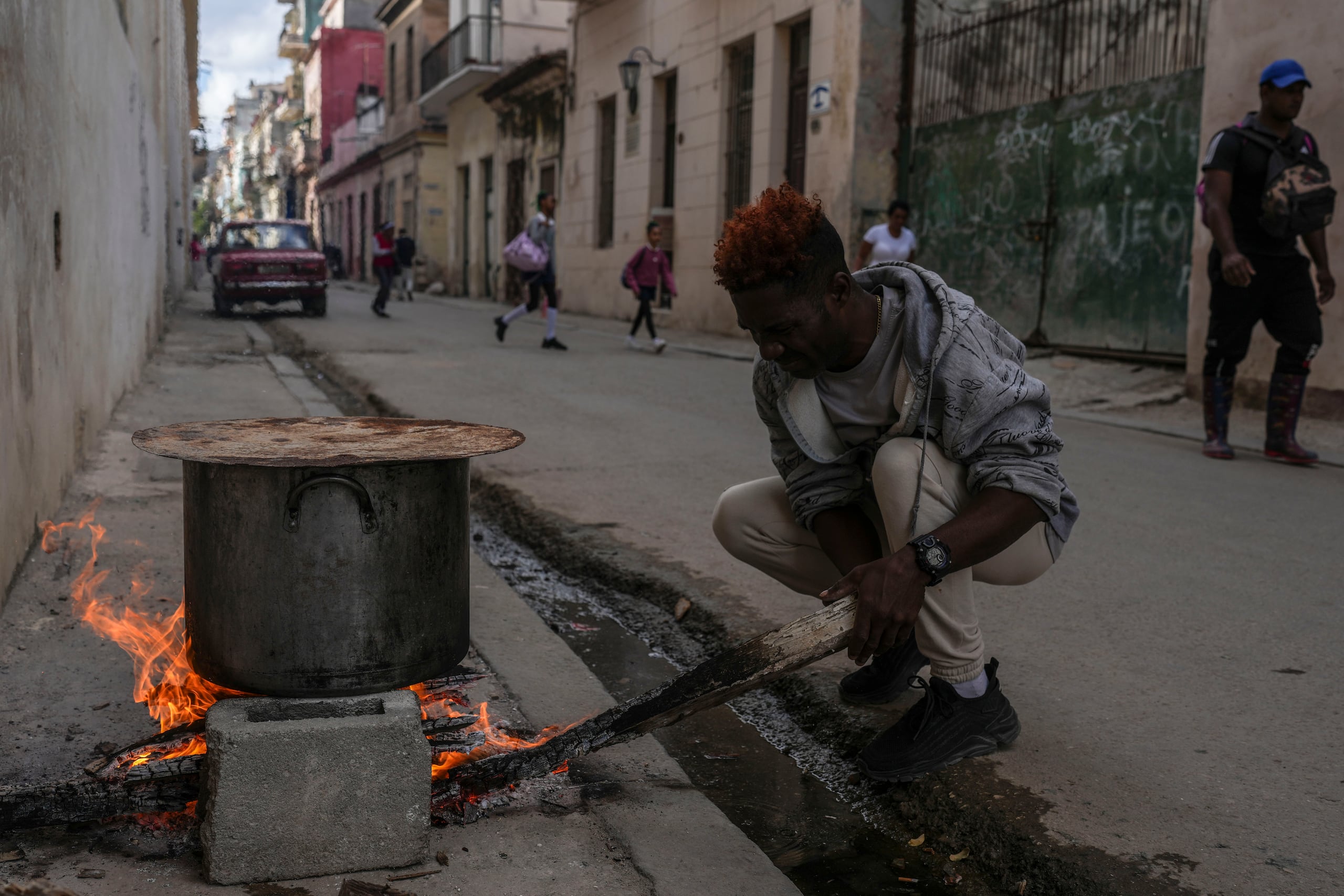 Un hombre cocina sopa sobre una fogata en una acera durante un apagón en La Habana, Cuba, el miércoles 4 de diciembre de 2024.