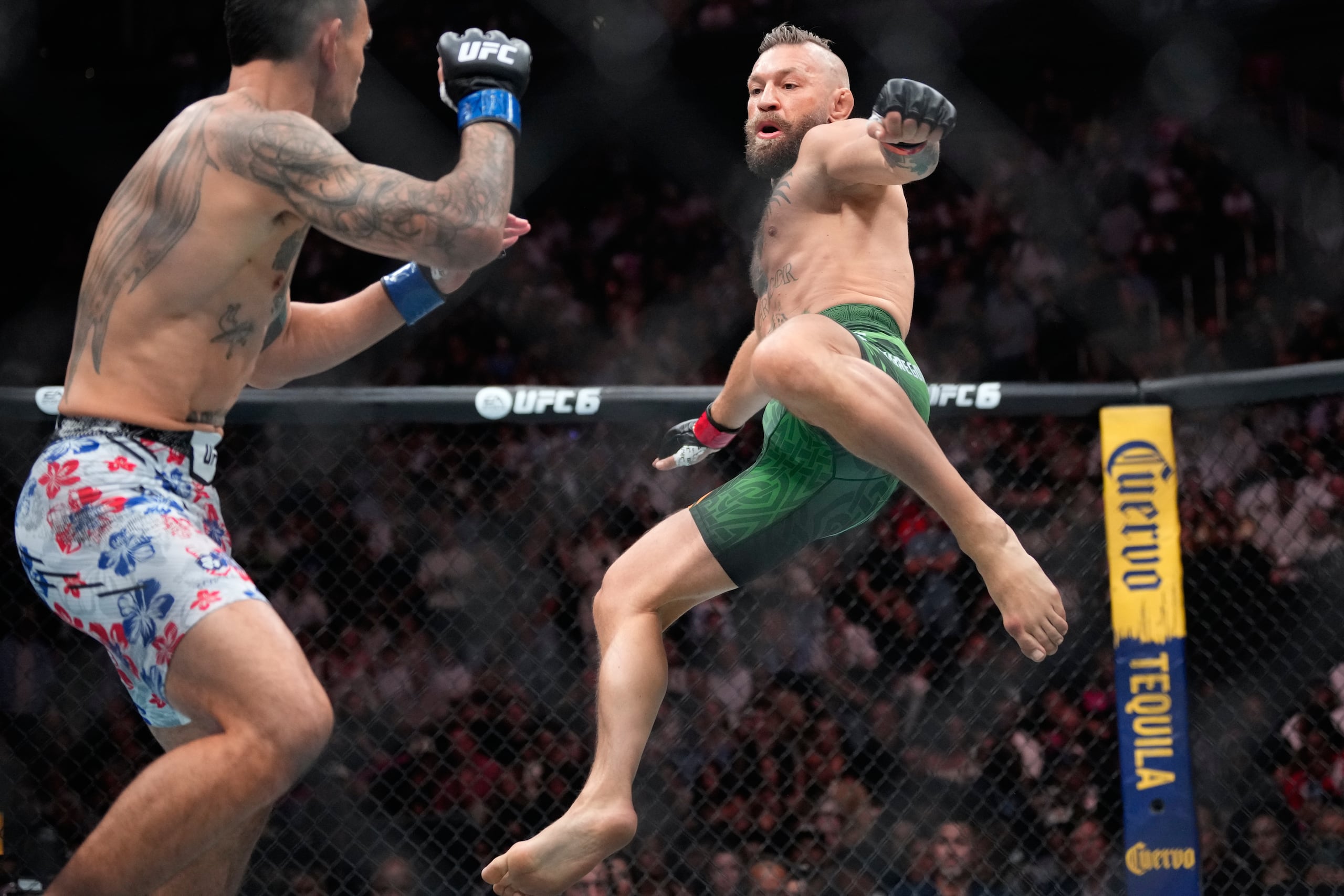 Conor McGregor, a la derecha, salta para dar una patada mientras pelea contra Max Holloway en un combate de peso wélter.