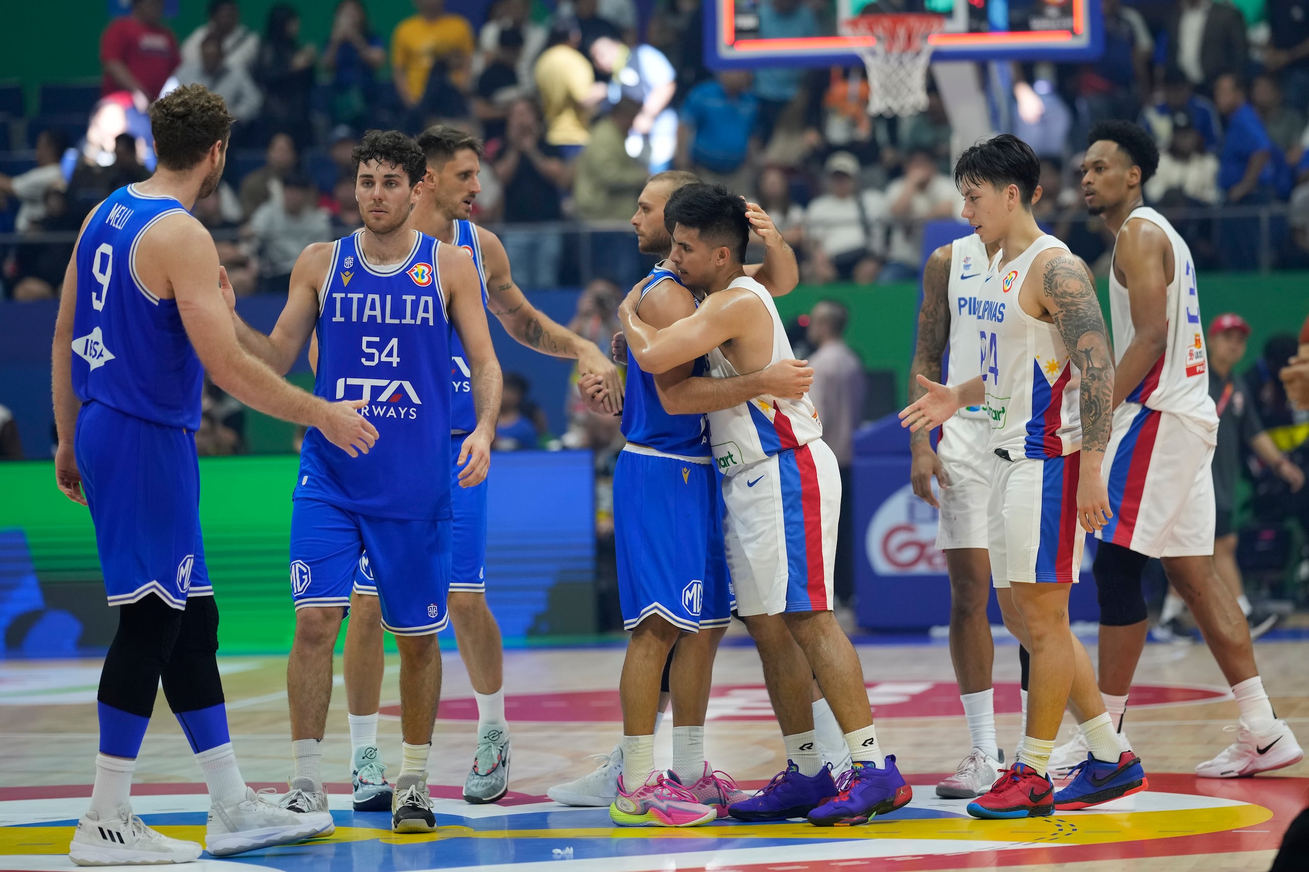 El defensa de Italia, Marco Spissu (0), y Kiefer Ravena (4), de Filipinas, se abraza luego de un juego en la fase preliminar.