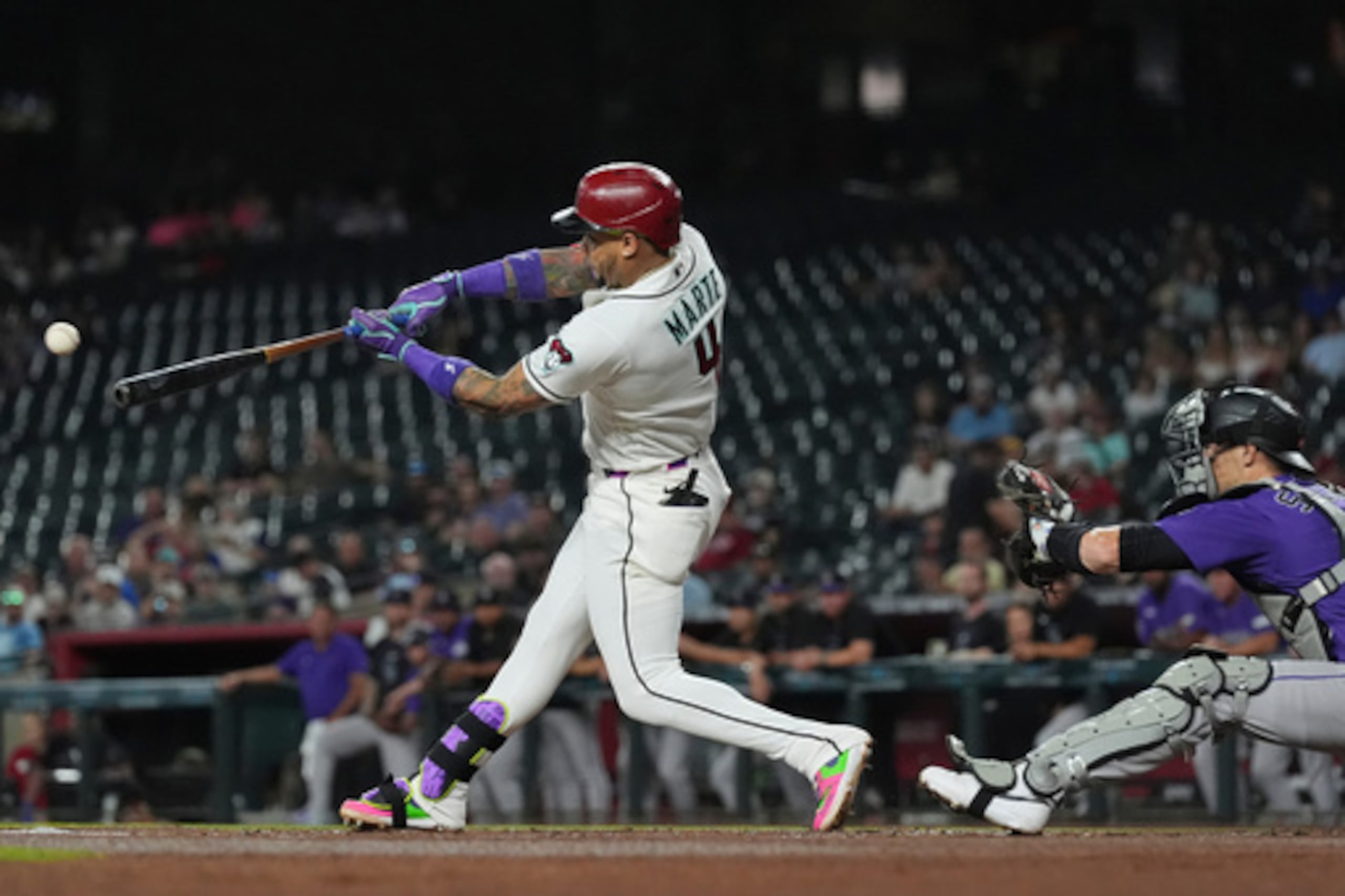 Ketel Marte (4), de los Arizona Diamondbacks, batea un sencillo que impulsa una carrera mientras el receptor de los Colorado Rockies, Brett Sullivan, intenta atrapar la pelota durante la primera entrada de un partido de béisbol, el miércoles 12 de agosto de 2026, en Phoenix. (Foto AP/Ross D. Franklin)