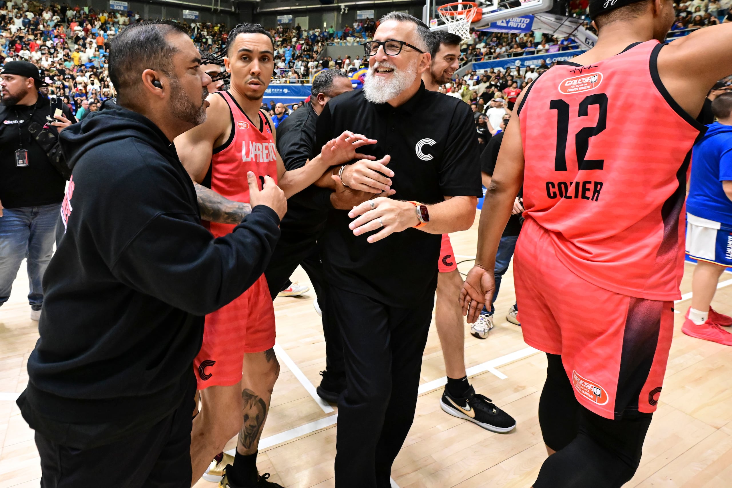 El dirigente Wilhelmus Caanen y los jugadores de los Criollos de Caguas durante una atropellada salida del tabloncillo en la que les lanzaron vasos, tras culminar el sexto juego de la final del BSN en Manatí.