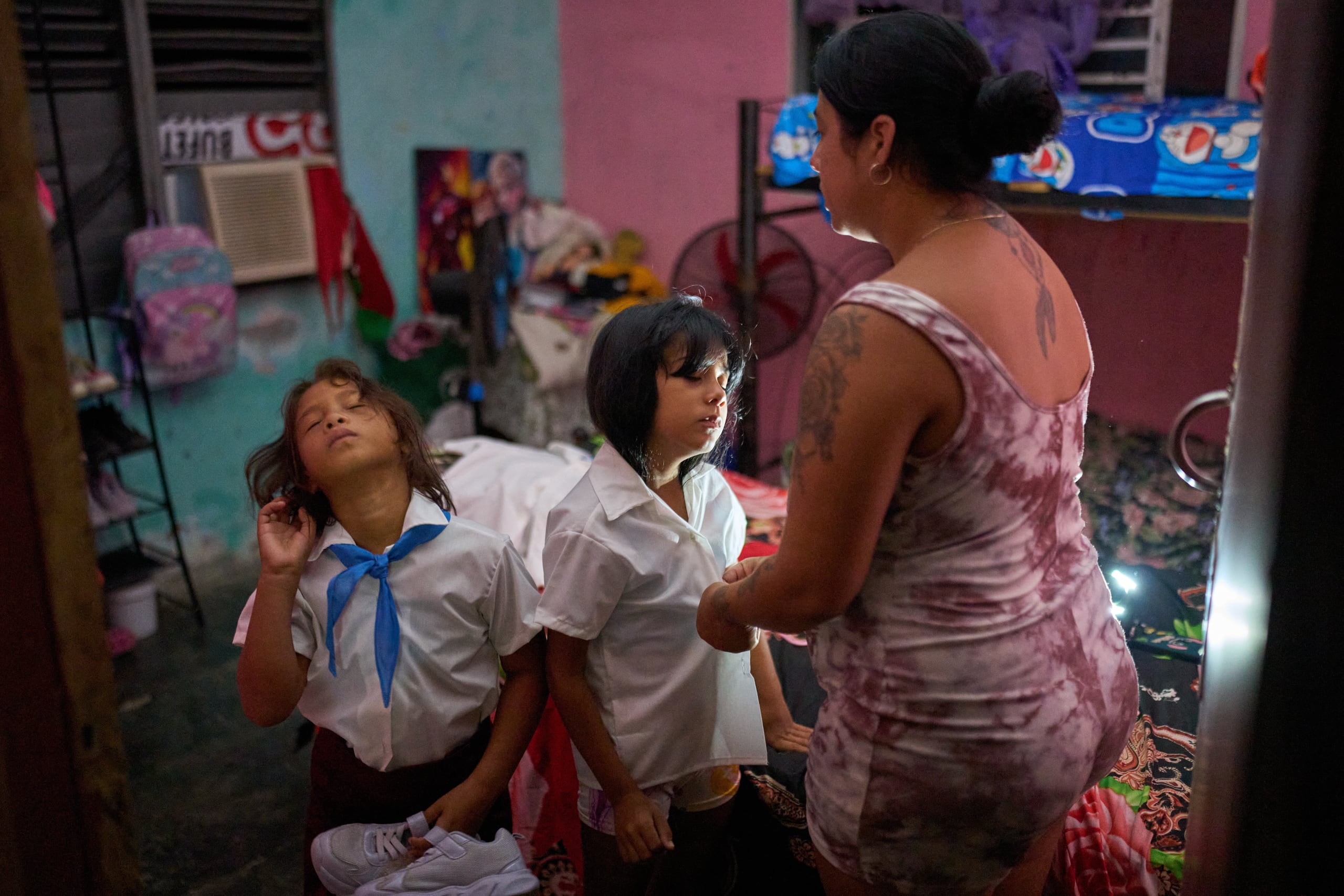Yurima Izaguirre prepara a dos de sus hijos para su regreso a clases utilizando la linterna de su teléfono celular para iluminar la habitación durante un apagón en Minas, en la provincia de La Habana, Cuba, el martes 1 de septiembre de 2026. (AP Foto/Ramón Espinosa)