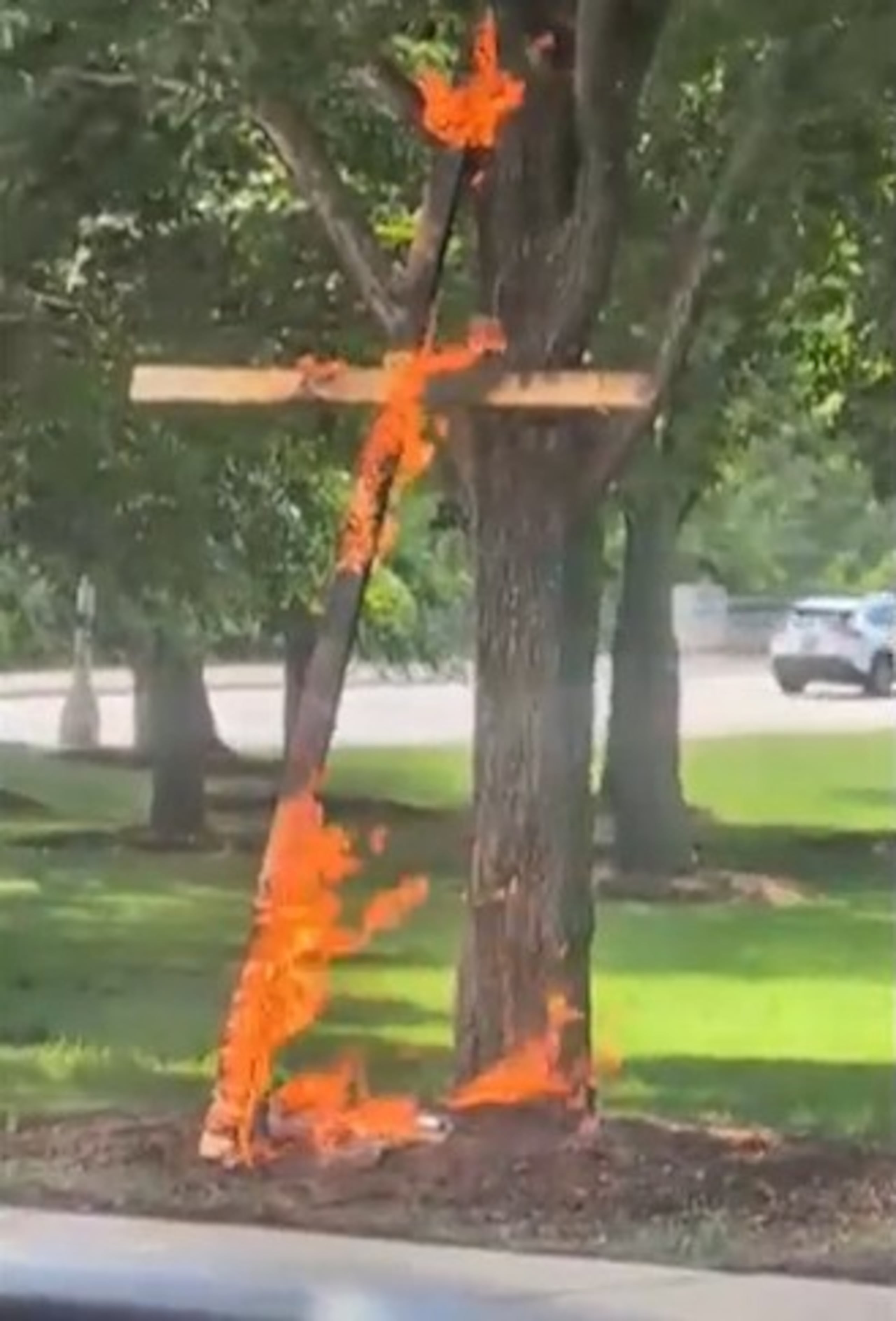 Esta escena de un video tomada por la conductora Keinika Carlton muestra una cruz de madera envuelta en llamas naranjas, apoyada sobre un árbol en Grant Park, Chicago, Illinois, el martes 9 de julio de 2026.(Keinika Carlton via AP)