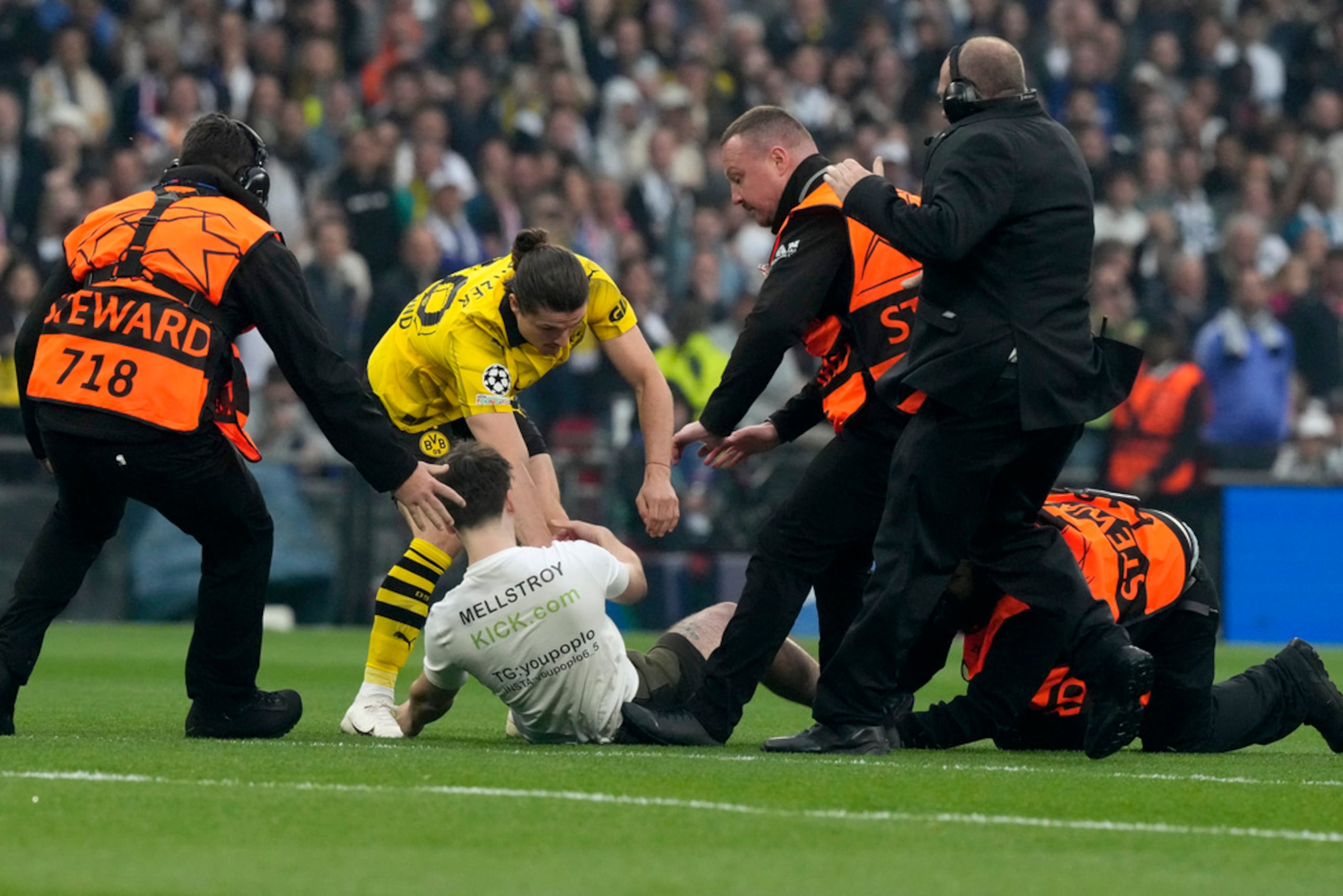 Marcel Sabitzer (al centro) y personal de seguridad persiguen a un invasor durante el partido entre Borussia Dortmund y Real Madrid en el Estadio Wembley en Londres.