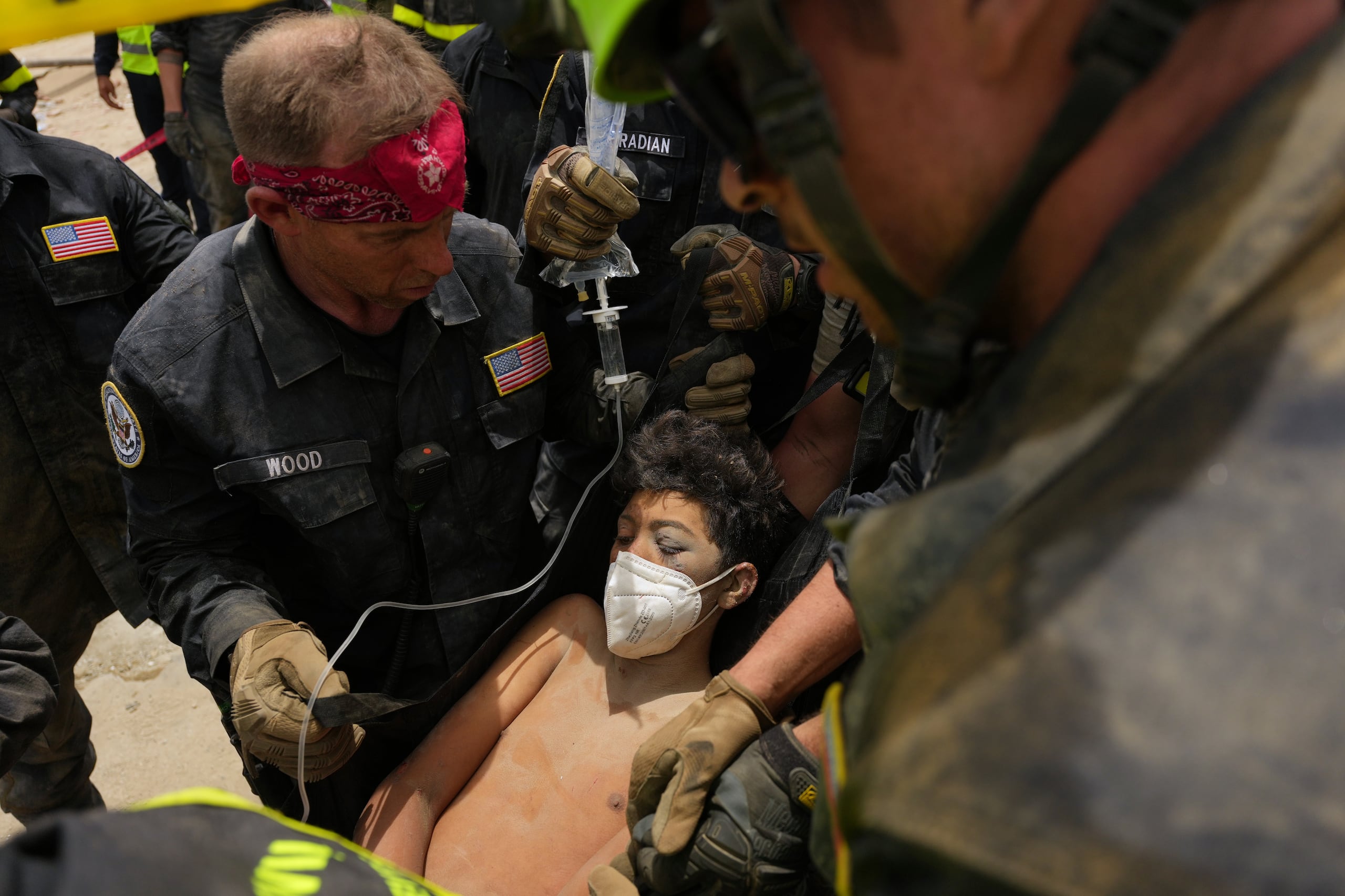 Bomberos estadounidenses del equipo de búsqueda y rescate del condado de Fairfax sacan a un niño de entre los escombros tras rescatarlo a él y a su padre de un edificio que se derrumbó durante los terremotos en La Guaira, Venezuela, el domingo 28 de junio de 2026. (Foto AP/Matias Delacroix)