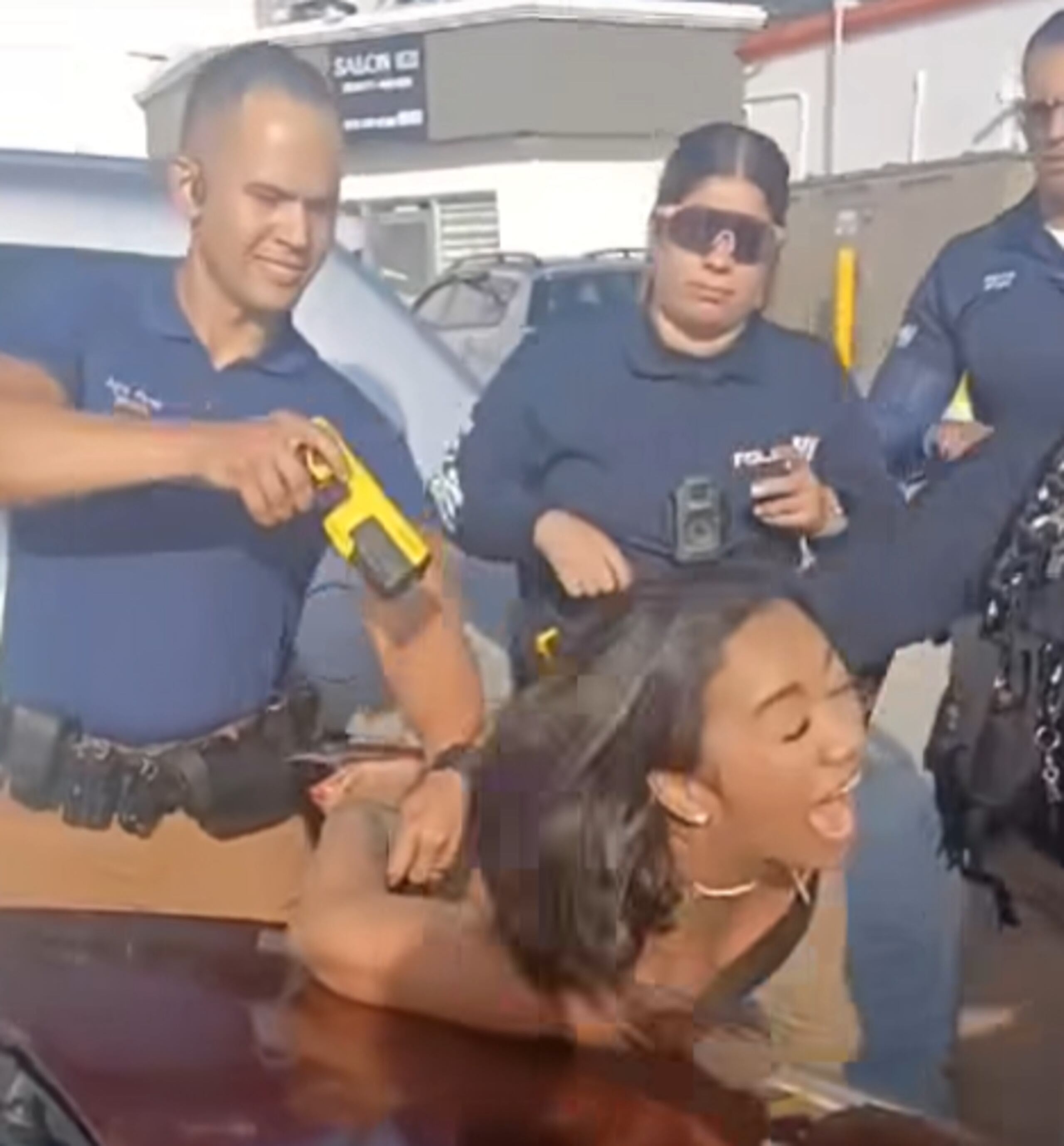 Captura del momento en que el agente le dispara con un taser a la mujer esposada.