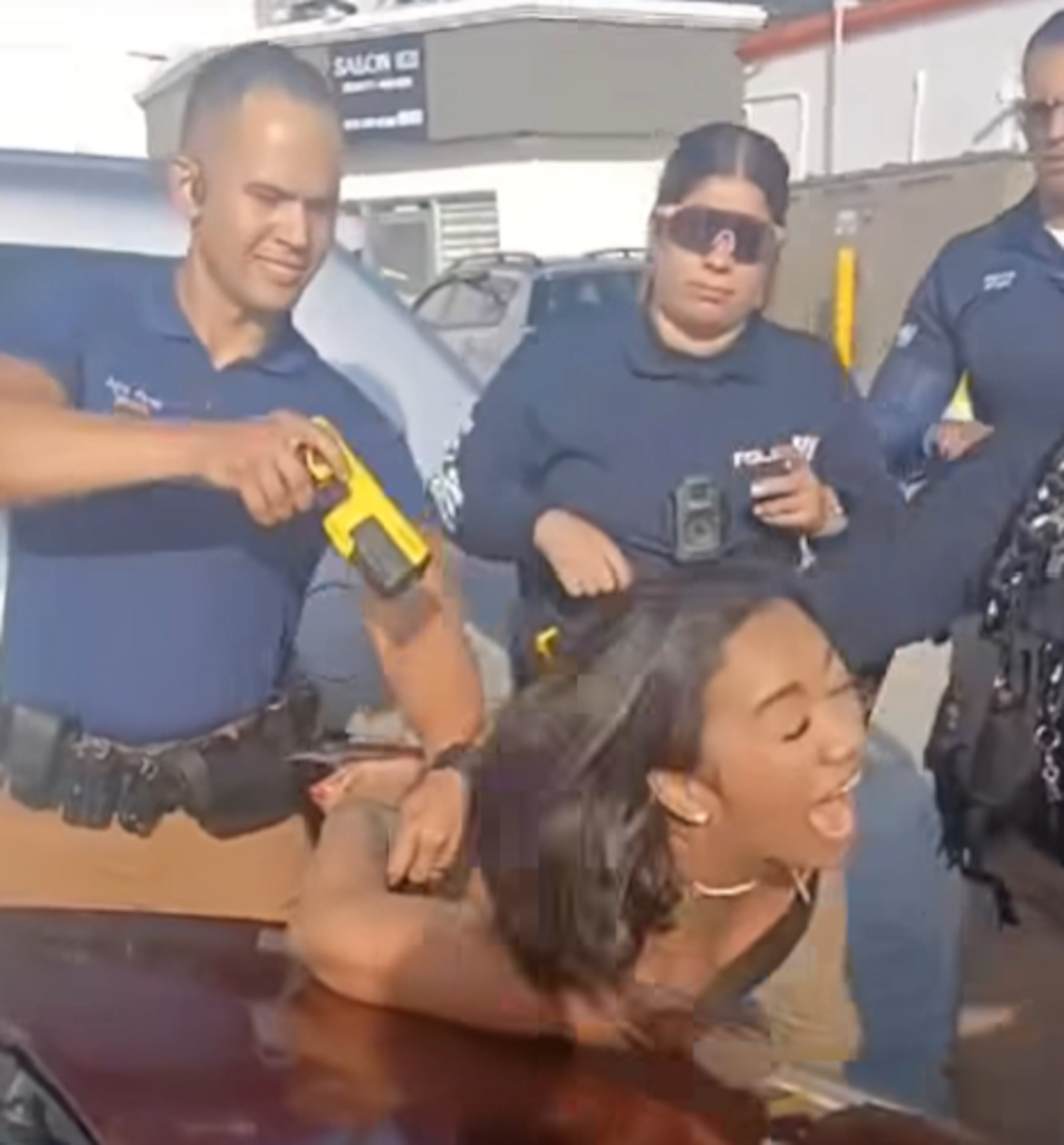 Captura del momento en que el agente le dispara con un taser a la mujer esposada.