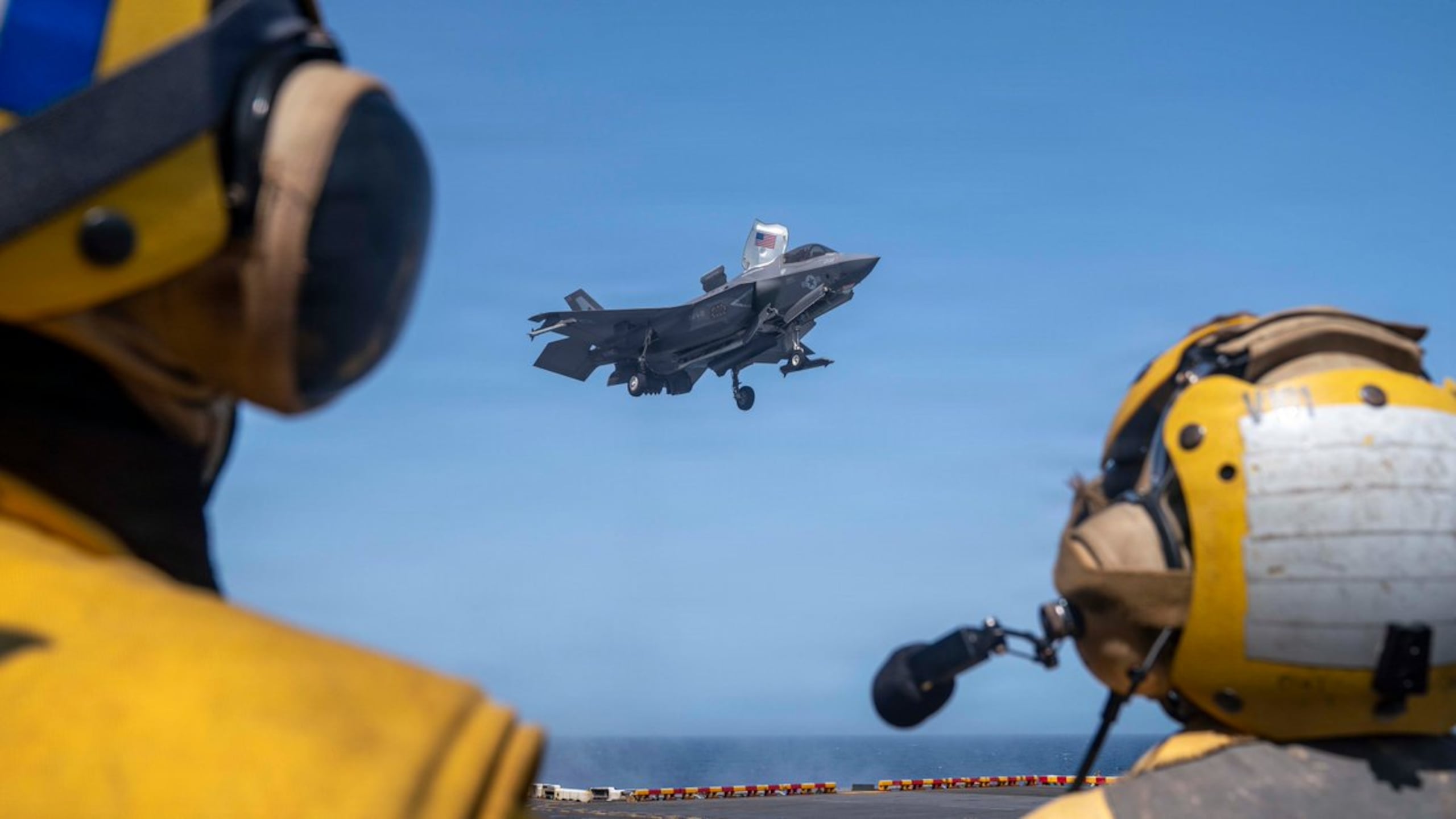 Soldados de la Marina de Estados Unidos observan cómo un caza furtivo F-35B del Cuerpo de Marines aterriza en la cubierta de vuelo del USS Tripoli (LHA 7) mientras navega por el mar Arábigo.