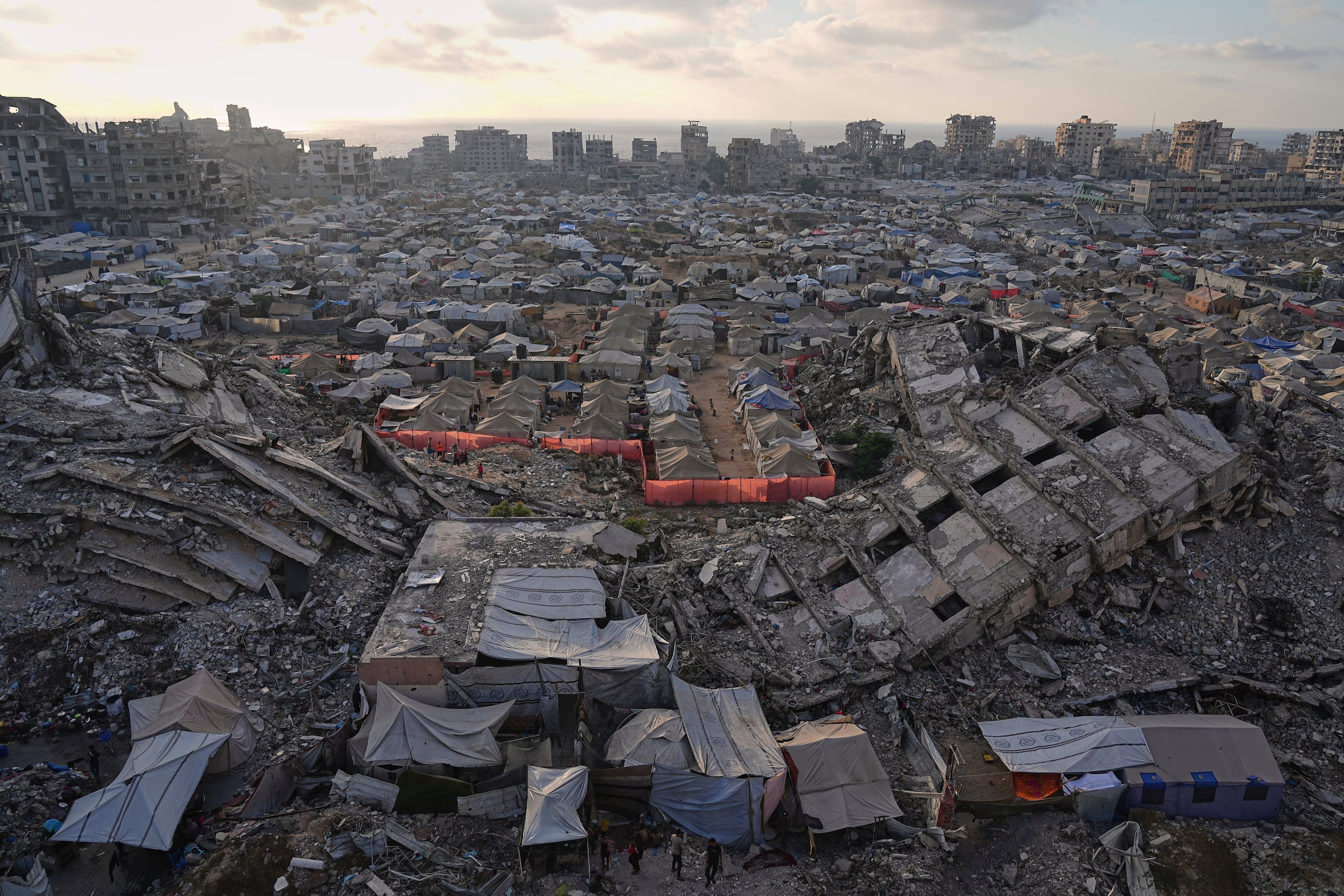 Un campamento de tiendas de campaña para palestinos desplazados se extiende entre las ruinas de edificios destruidos por los bombardeos israelíes, el sábado 21 de junio de 2025, en el oeste de Ciudad de Gaza. (AP Foto/Jehad Alshrafi, Archivo)