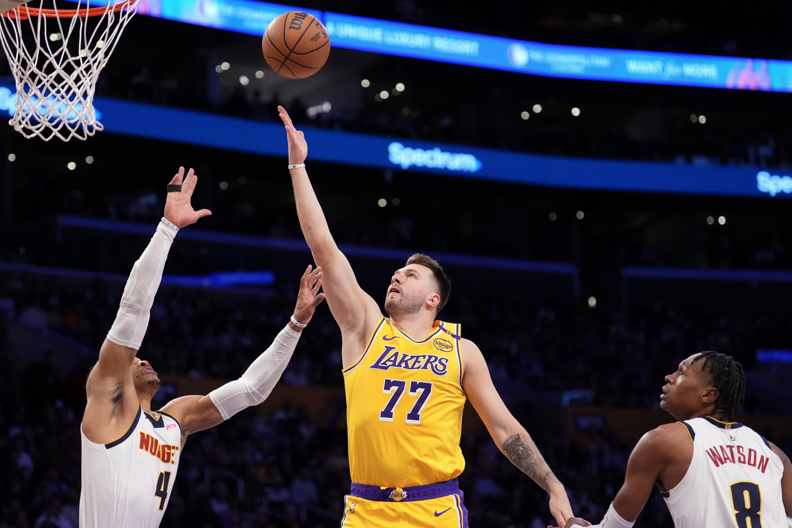 Luka Doncic, de los Lakers de Los Ángeles, dispara frente a Russell Westbrook, y Peyton Watson, de los Nuggets de Denver.
