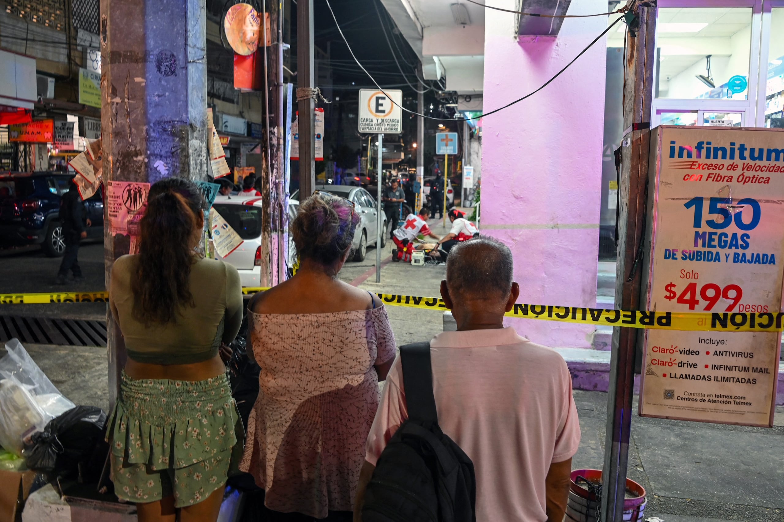 People look at as Red Cross paramedics attend the body journalist Jose Carlos Gonzalez, known on social media as "El Guerrero," who was shot dead in Acapulco, Guerrero state, Mexico on May 15, 2025. A journalist who ran a Facebook page for news, satire, and citizen reporting was murdered in the southern Mexican resort of Acapulco. (Photo by Francisco ROBLES / AFP)