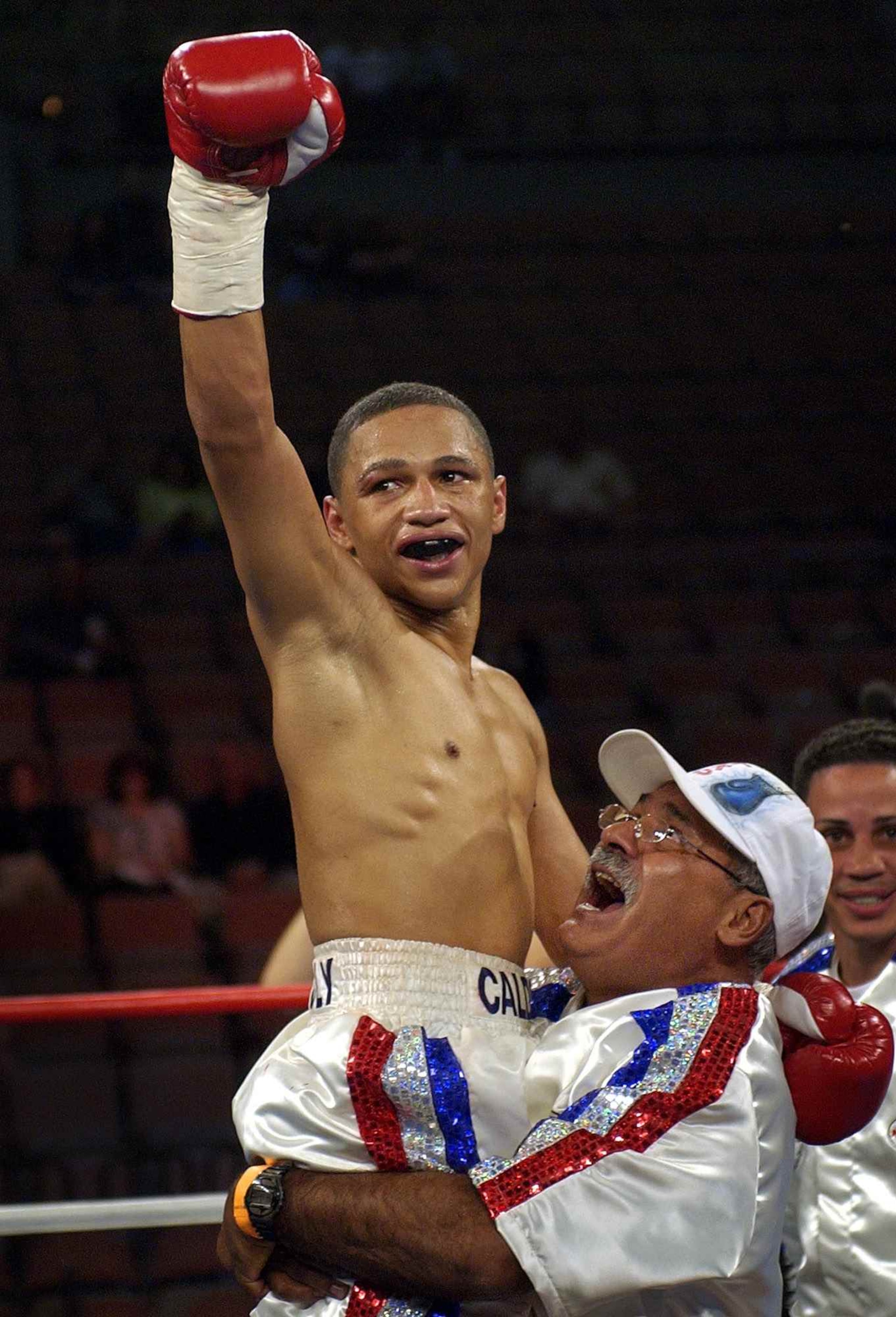 Iván Calderón es levantado por su entrenador José Sánchez tras derrotar al campeón de las 105 libras, Eduardo Márquez , en el 2003. (AP/Archivo)