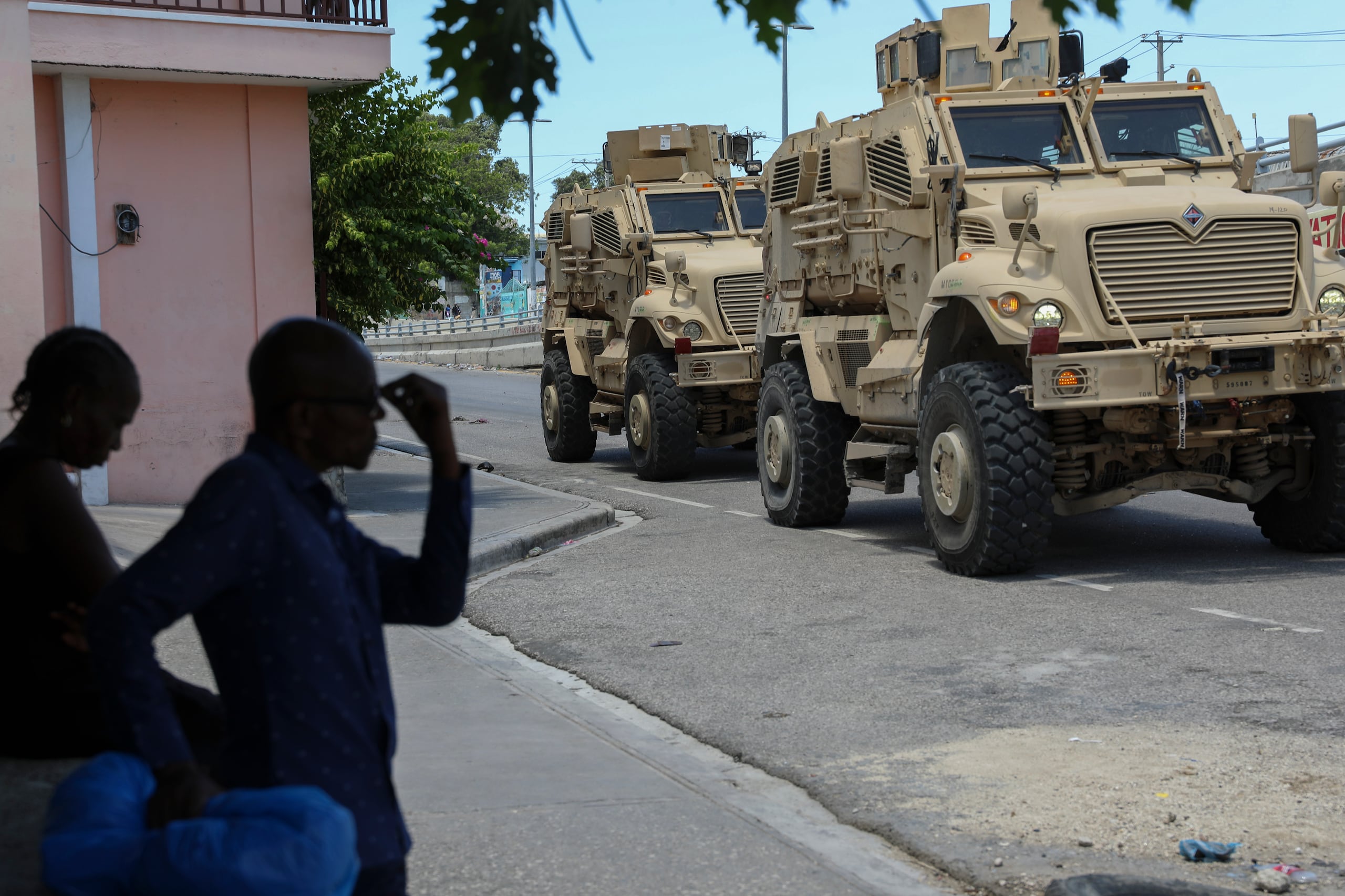Policías kenianos, que forman parte de una fuerza multinacional respaldada por la ONU, pasan frente a varios residentes en vehículos blindados en las calles de Puerto Príncipe, Haití, el miércoles 4 de septiembre de 2024.