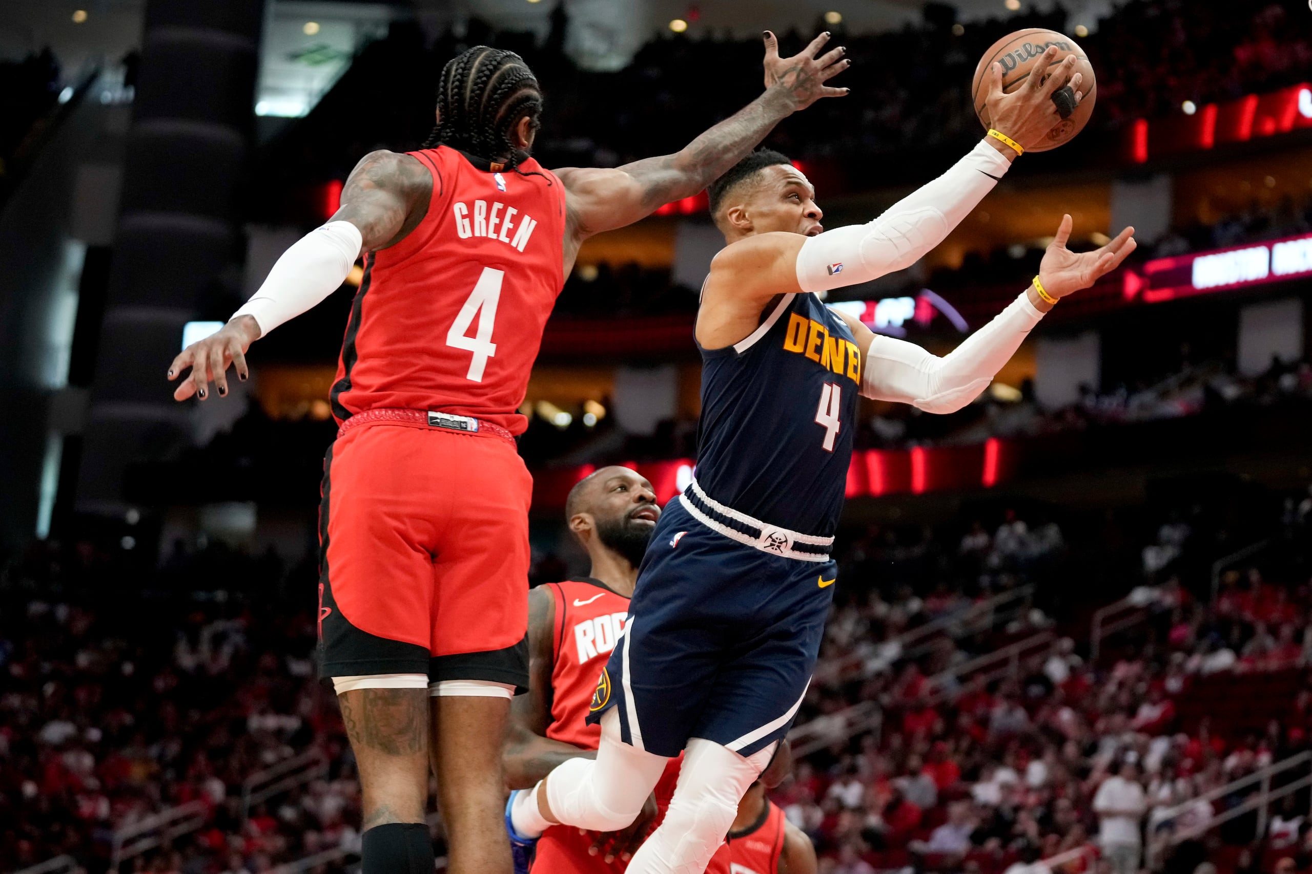 El escolta de los Nuggets de Denver, Russell Westbrook, a la derecha, conduce hacia la canasta superando al escolta de los Rockets de Houston, Jalen Green.