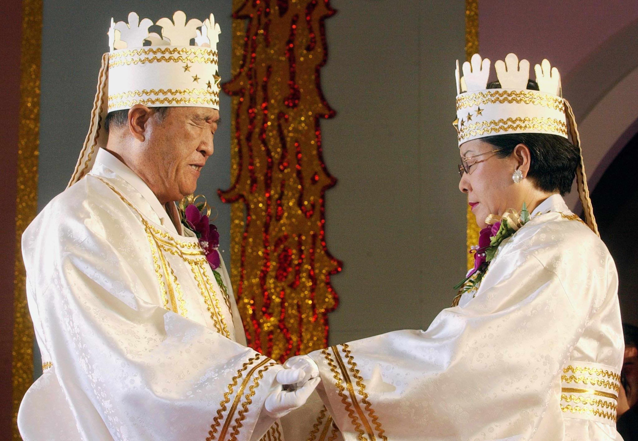 El fundador de la Iglesia de la Unificación, el reverendo Sun Myung Moon (izquierda), y su esposa Hak Ja Han Moon se toman de las manos para bendecir a las parejas durante una ceremonia de bodas masivas el 16 de febrero de 2002 en un estadio de Seúl.