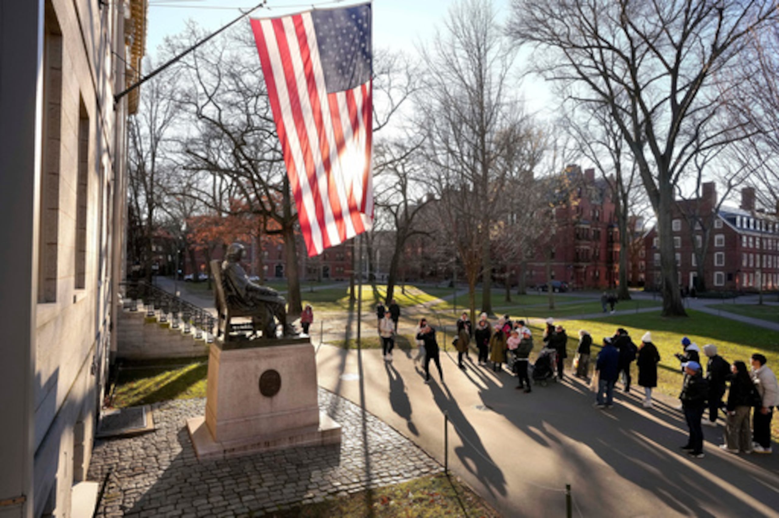 ARCHIVO - Varias personas se hacen fotos junto a una estatua de John Harvard, a la izquierda, en el campus de la Universidad de Harvard, el 2 de enero de 2024, en Cambridge, Massachusetts. (Foto AP/Steven Senne, archivo)