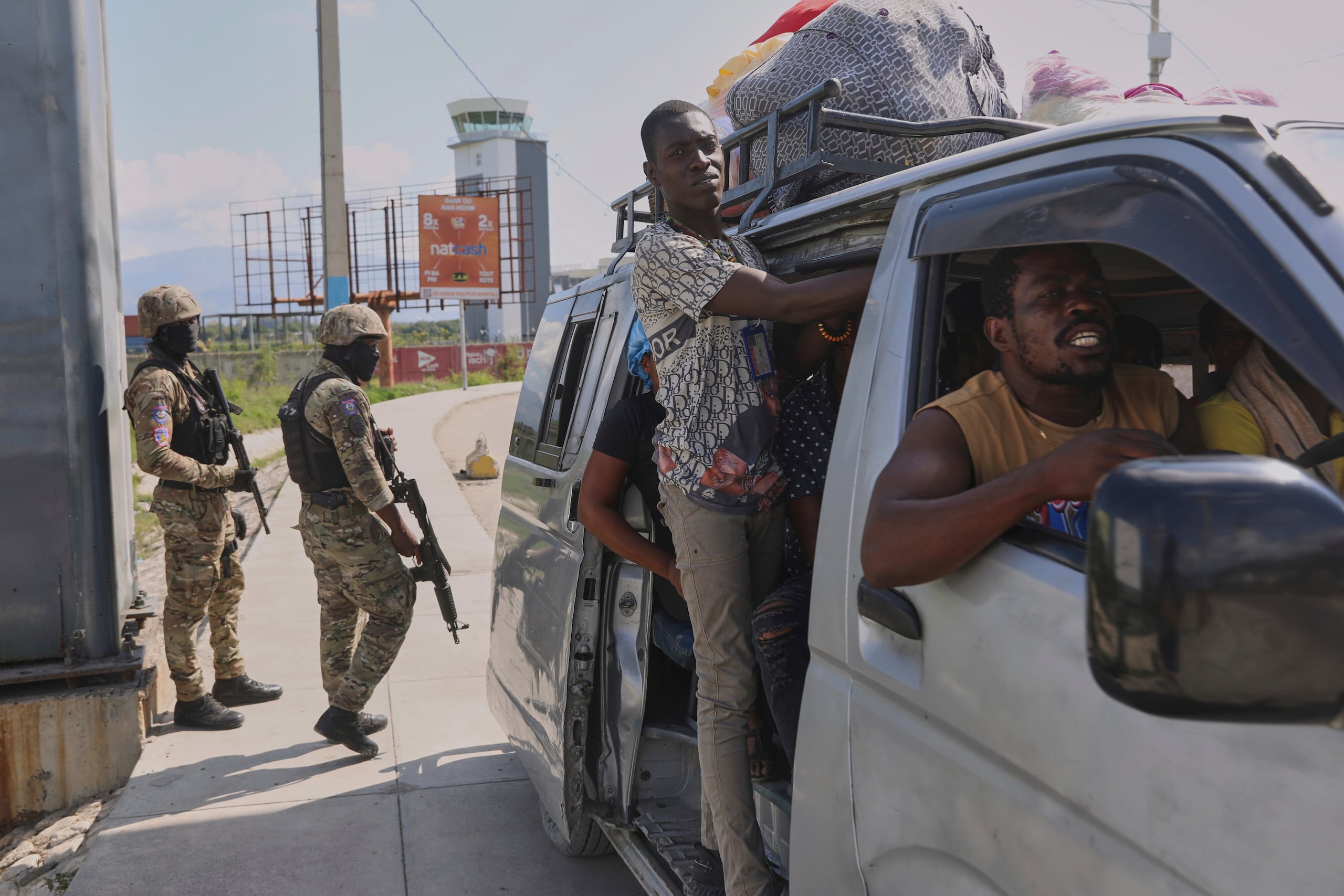Un grupo de personas pasa frente a varios policías que patrullan una intersección, en Puerto Príncipe, Haití, el viernes 9 de mayo de 2025. (AP Foto/Odelyn Joseph)
