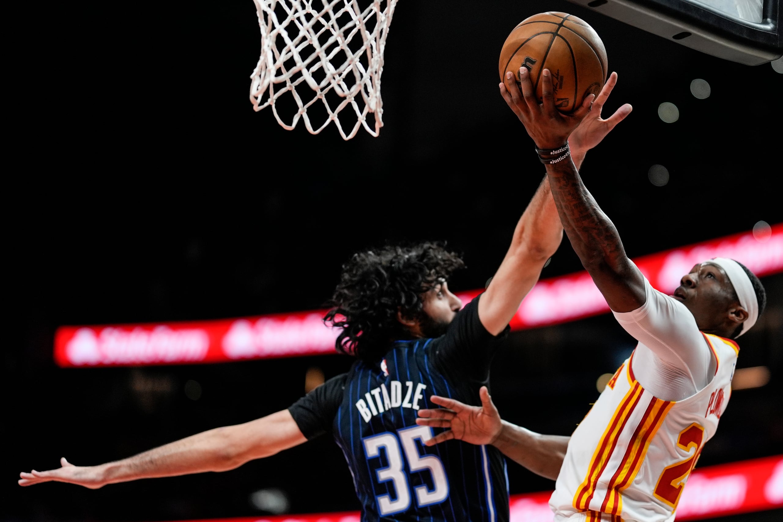 El base de los Hawks de Atlanta Daeqwon Plowden lanza el balón frente al pívot del Magic de Orlando Goga Bitadze en el encuentro del domingo 13 de abril del 2025. (AP Foto/Mike Stewart)