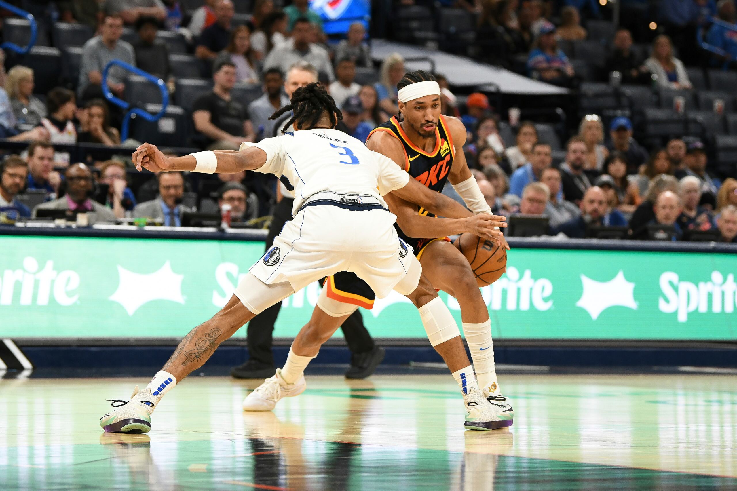 Aaron Wiggins, derecha, del Thunder de Oklahoma City, lleva el balón y busca a quien pasarlo, mientras Alex Fudge (3) de los Mavericks de Dallas, presiona durante la segunda mitad del juego de baloncesto de la NBA, el domingo 14 de abril de 2024, en Oklahoma City. (AP Foto/Kyle Phillips)