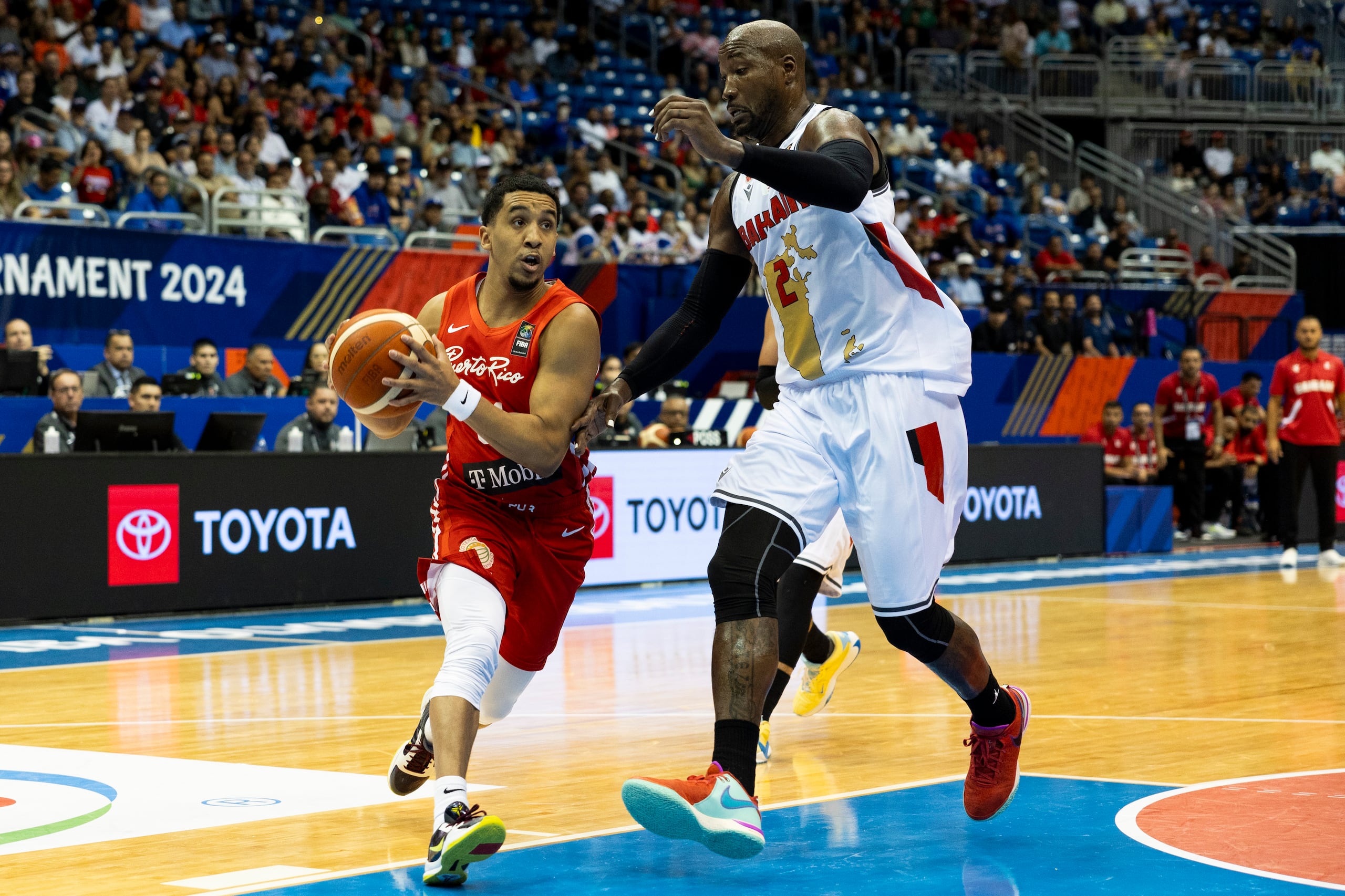 Tremont Waters protege el balón ante la defensa de Wayne Chism en una penetración durante la primera mitad del partido ante Baréin en el Coliseo José Miguel Agrelot.