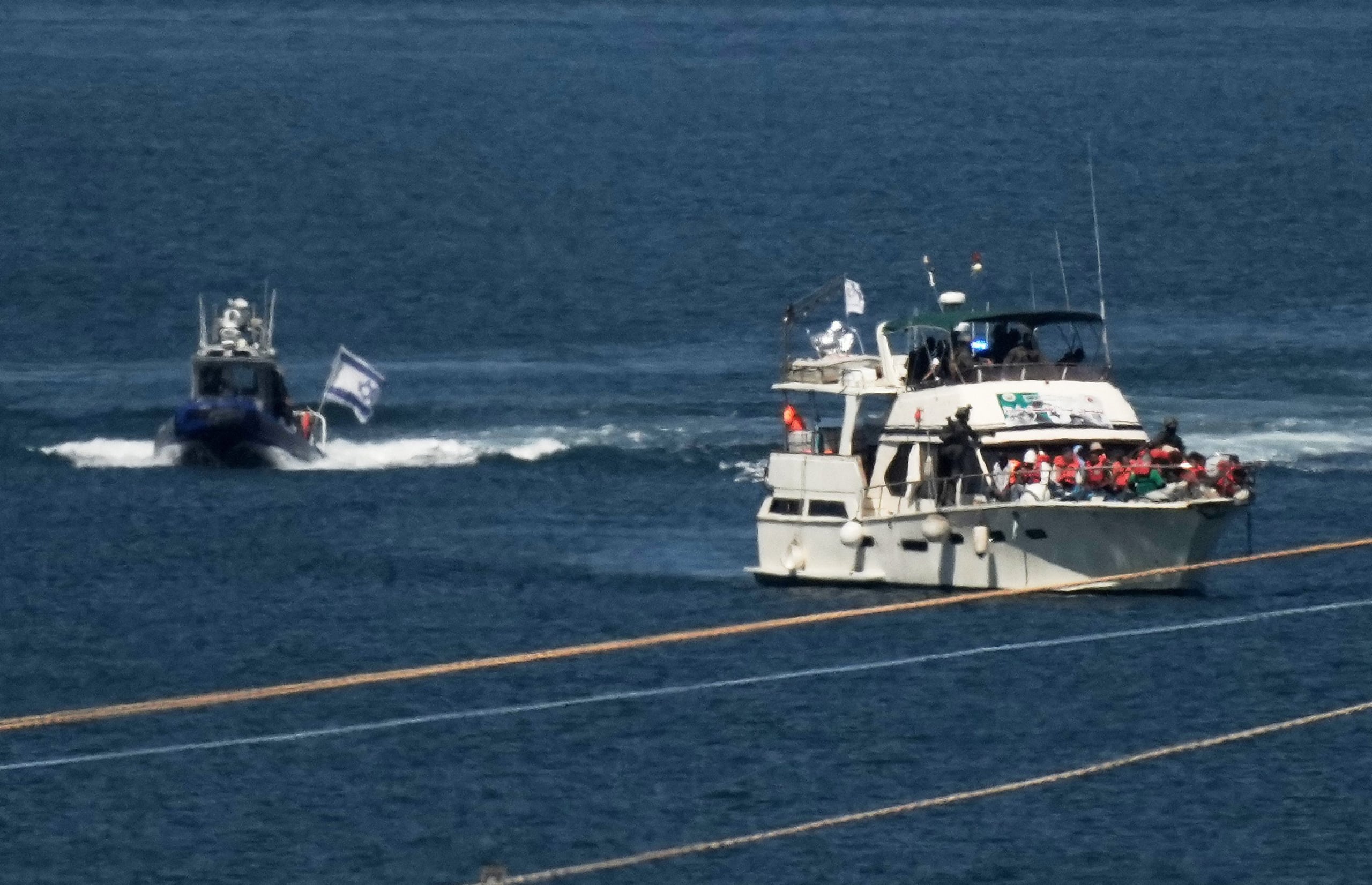 Activistas con chalecos salvavidas color anaranjado a bordo de un barco de la Flotilla Sumud con destino a Gaza mientras soldados de la Armada de Israel lo escoltan a puerto, el 2 de octubre de 2025, en Ashdod, Israel, después de interceptar a la embarcación mientras se acercaba a la costa de Gaza. (AP Foto/Leo Correa, Archivo)