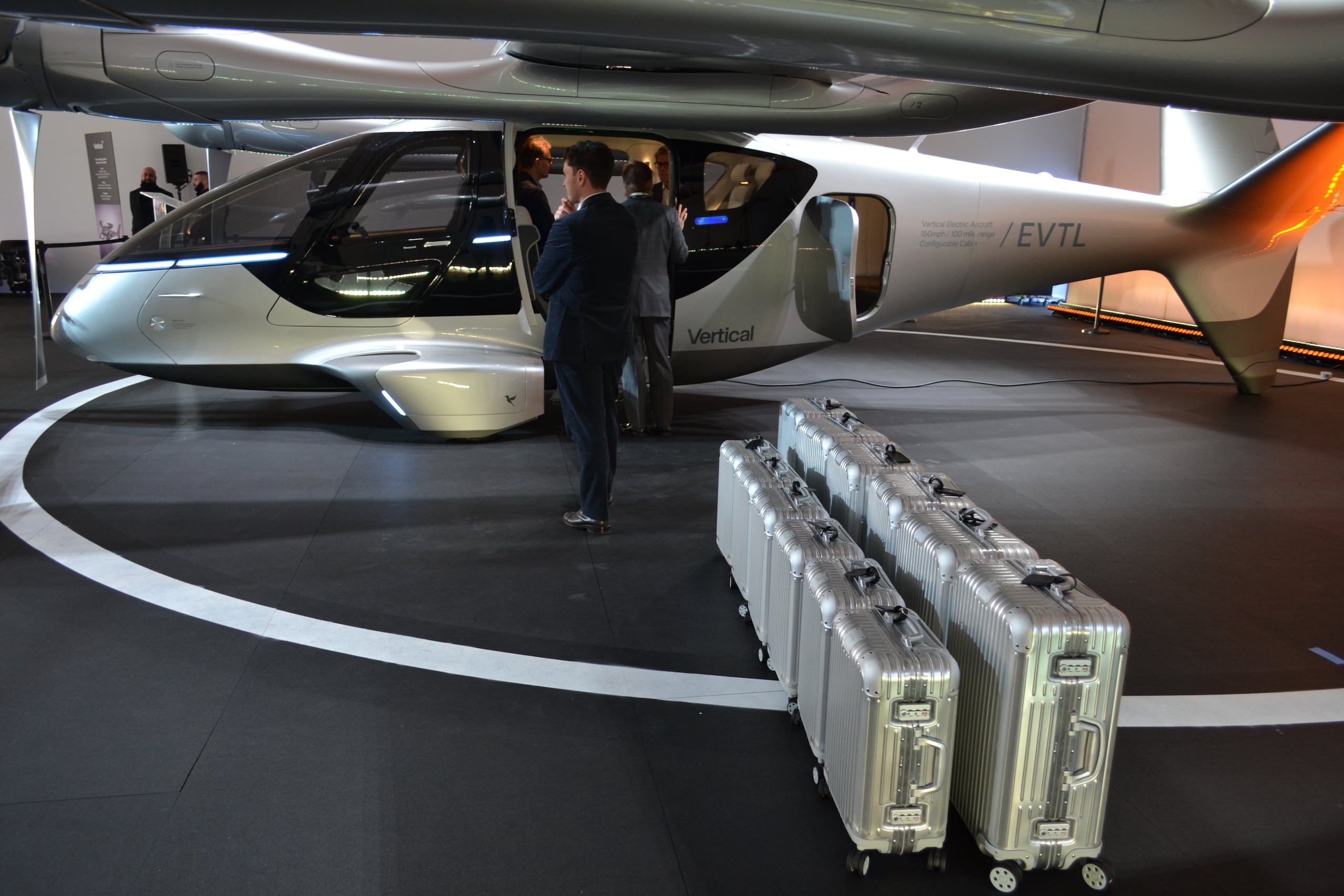 Unas personas preparan las maletas frente a un taxi volador eléctrico de la compañía Vertical Aerospace expuesto el 24 de febrero de 20126 en Miami Beach, Florida. (EFE/Antoni Belchi)