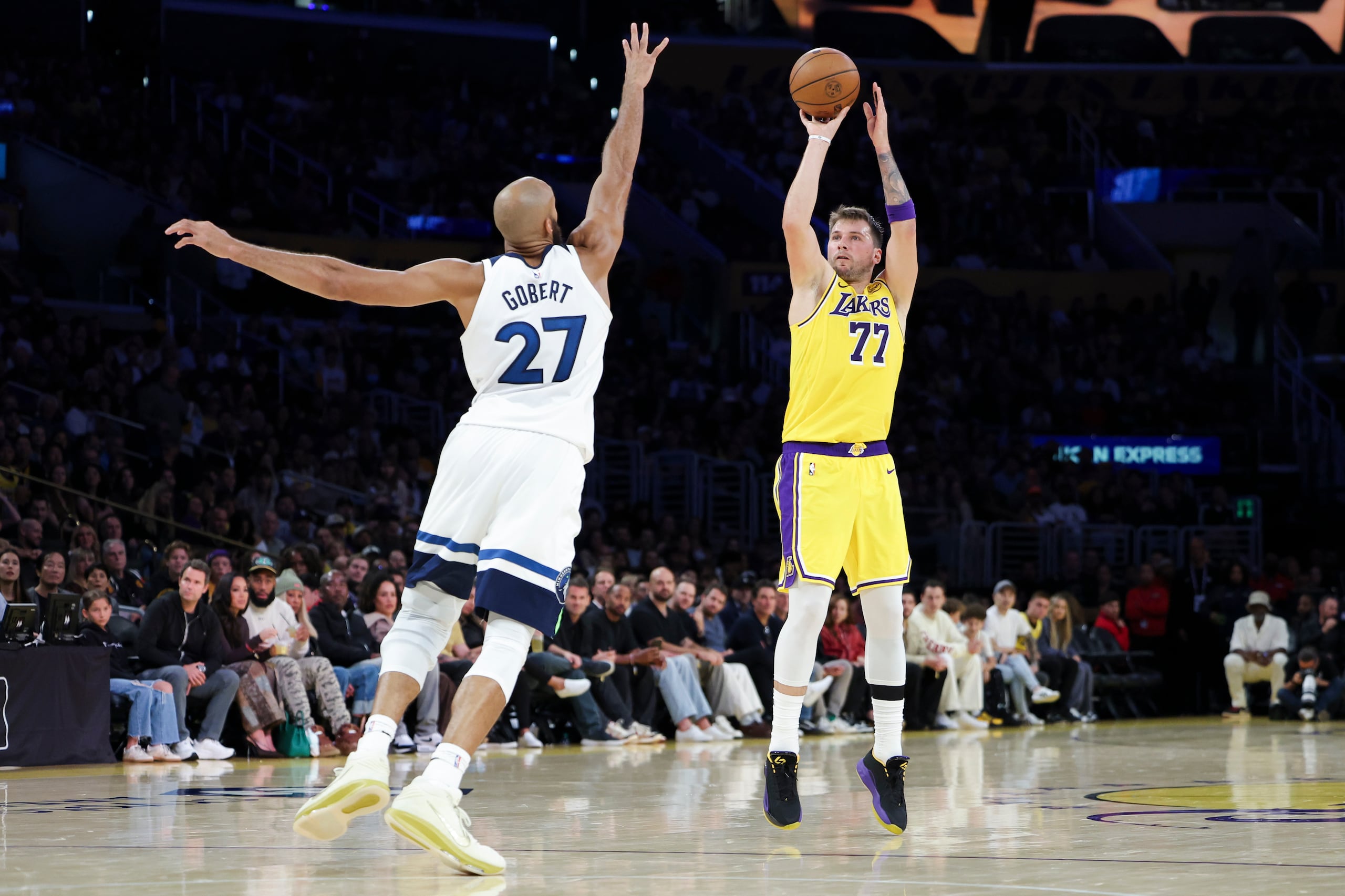 Luka Doncic (77), de los Lakers de Los Ángeles, dispara desde larga distancia frente a Rudy Gobert (27), de los Timberwolves de Minnesota, durante la primera mitad del partido de baloncesto de la NBA, el viernes 24 de octubre de 2025, en Los Ángeles. (AP Foto/Jessie Alcheh)
