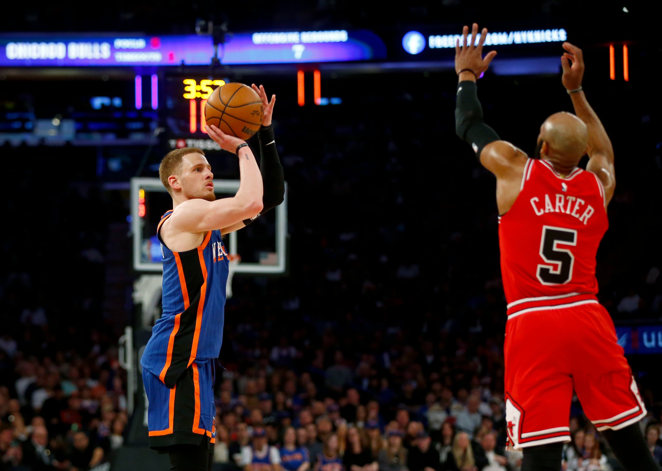 El base de los Knicks de Nueva York, Donte DiVincenzo, se prepara para lanzar un triple frente a Jevon Carter de los Bulls de Chicago.