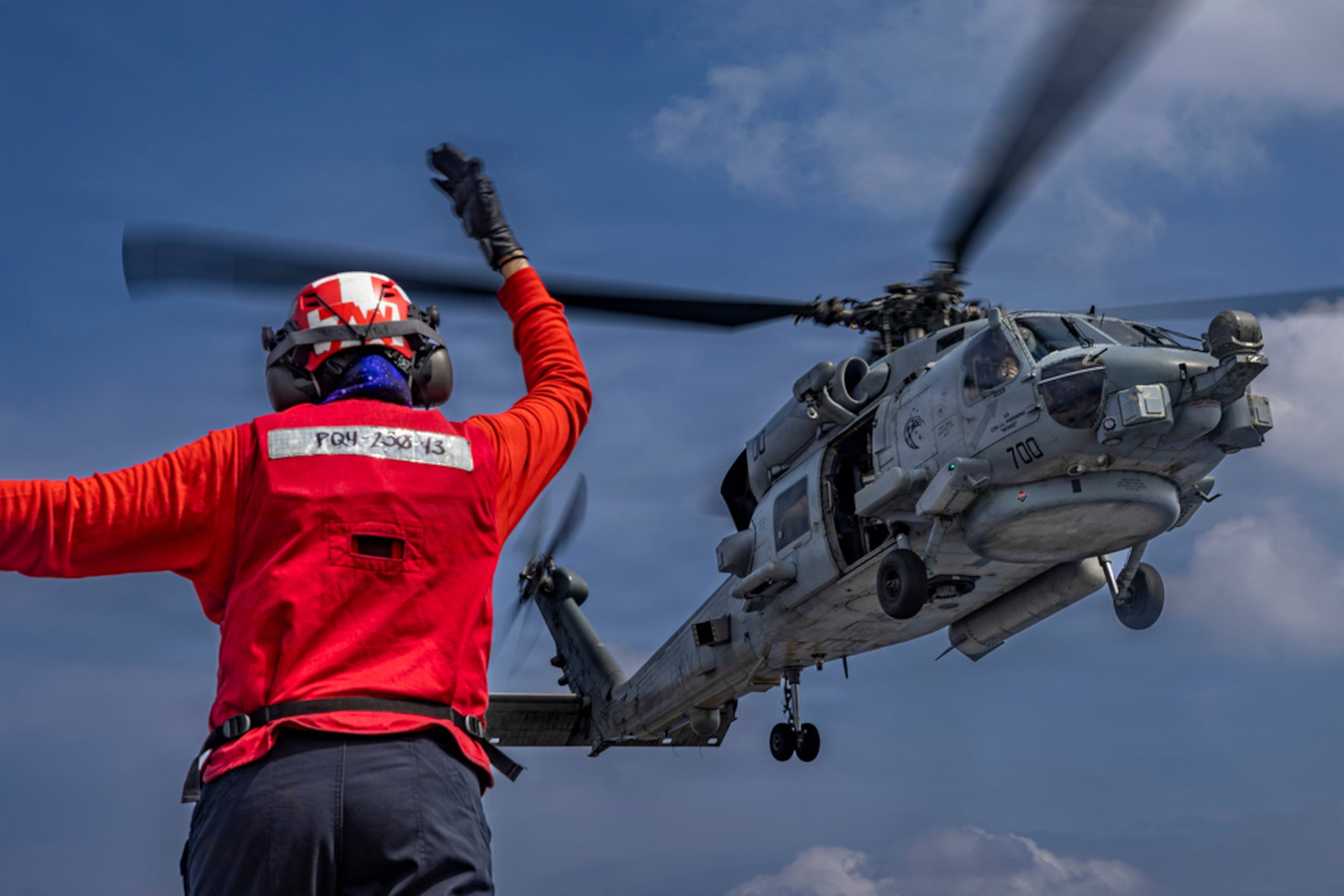 Esta foto, proporcionada por la Marina de Estados Unidos, muestra a la Aviation Ordnanceman de 3er Clase Dianna Hernández dirigiendo un helicóptero MH-60R Sea Hawk en la cubierta de vuelo del portaaviones de clase Nimitz USS Abraham Lincoln, en el océano Índico, el 21 de enero de 2026.