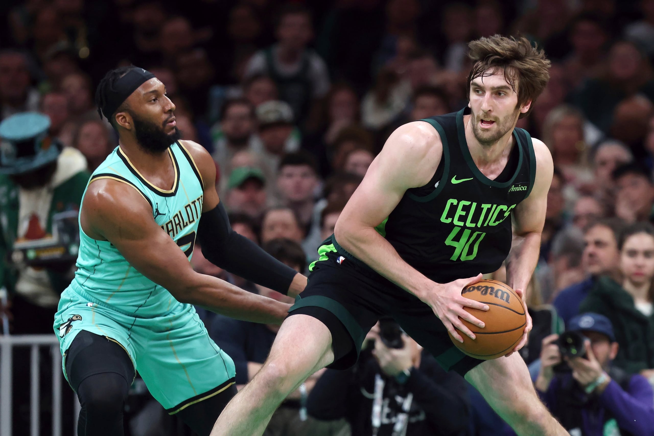 Luke Kornet de los Celtics de Boston avanza con el balón mientras lo defiende Josh Okogie de los Hornets de Charlotte en el encuentro de la NBA del domingo 13 de abril del 2025. (AP Foto/Michael Dwyer)