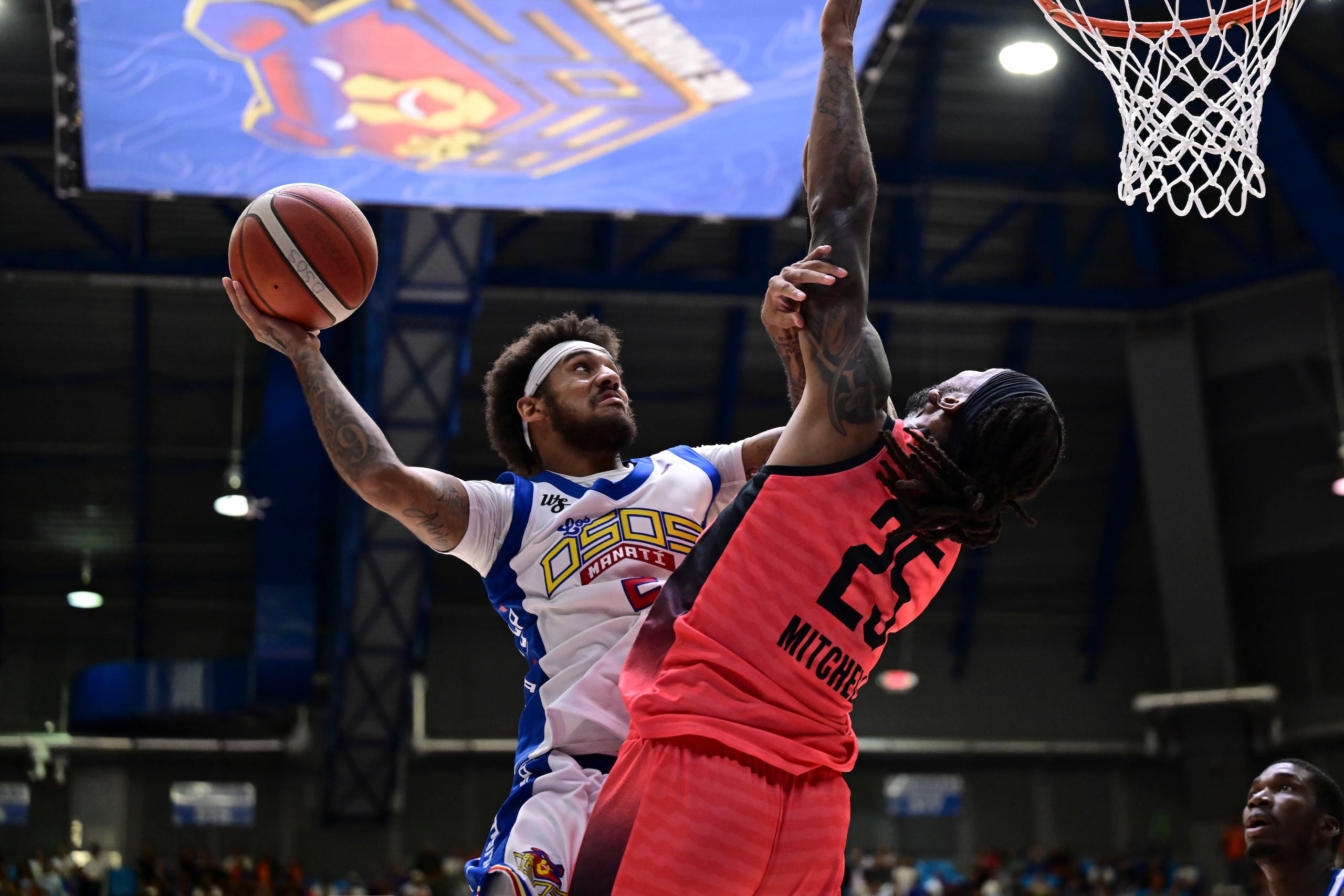Alexander Morales, de los Osos de Manatí, ataca al canasto frente a Akil Mitchell, de los Criollos de Caguas, durante la serie final 2024 del Baloncesto Superior Nacional (BSN).