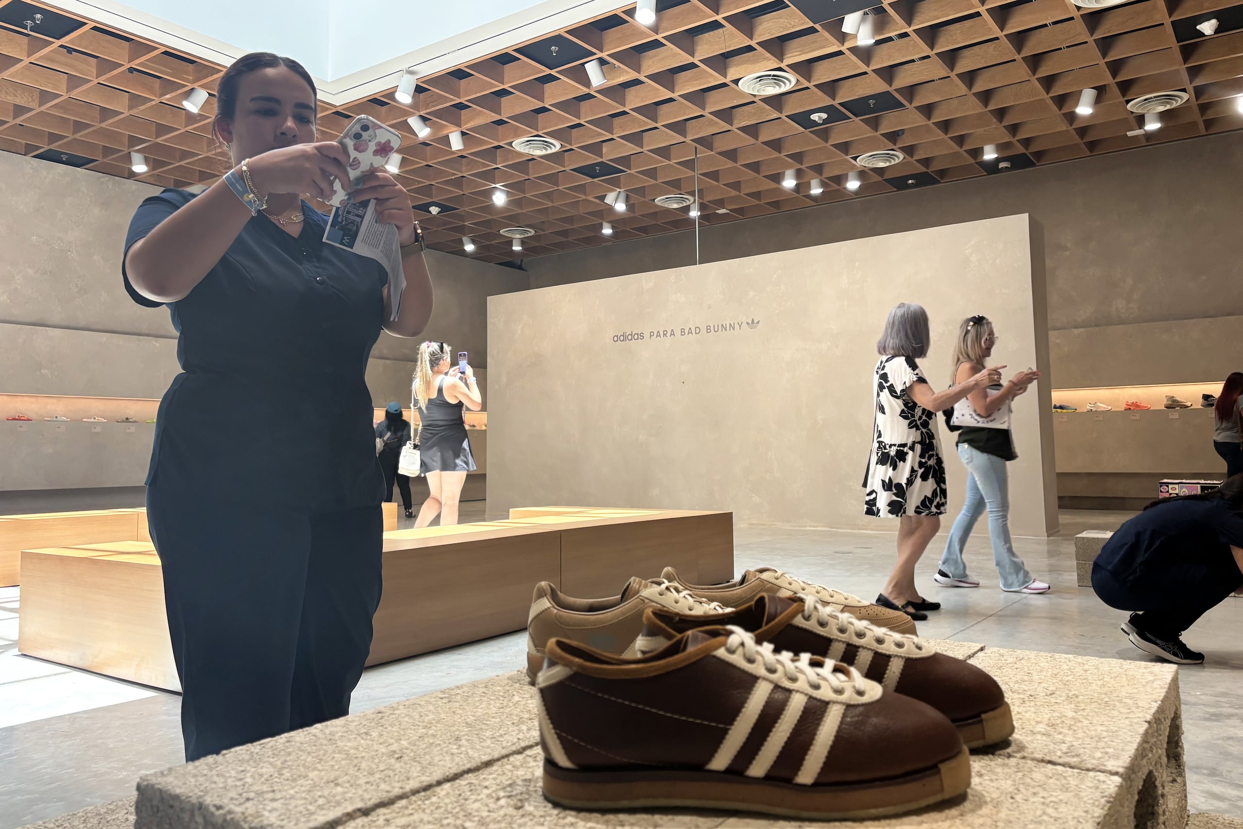 Una persona toma una fotografía a calzados Adidas de Bad Bunny durante la exposición "The Archive" en el Museo de Arte de Puerto Rico (MAPR), en San Juan. (EFE/ Esther Alaejos)