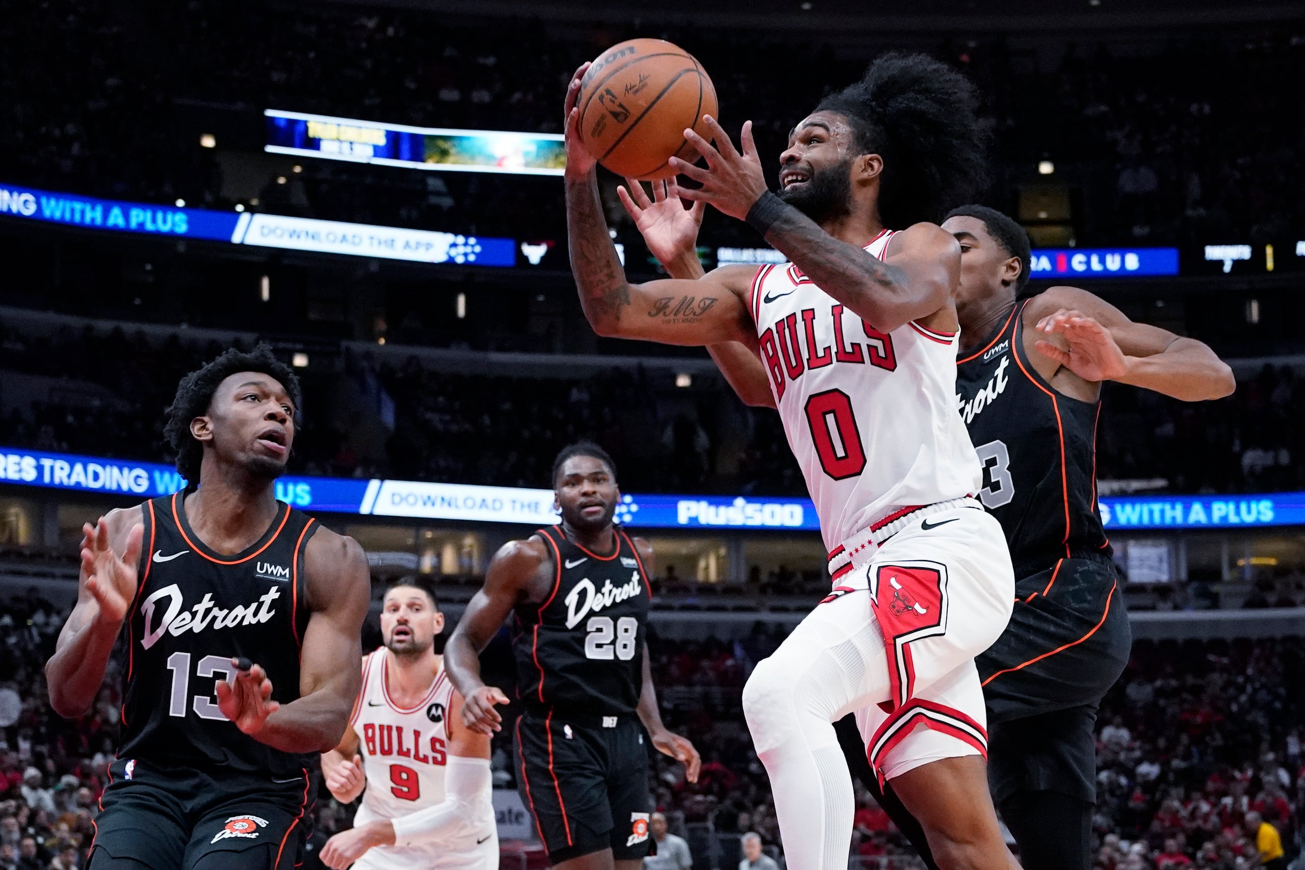 Coby White (0), de los Bulls de Chicago, se alista para encestar superando a Jaden Ivey y James Wiseman, izquierda, de los Pistons de Detroit, durante la primera mitad del juego de baloncesto de la NBA, en Chicago, el domingo 12 de noviembre de 2023. (AP Foto/Nam Y. Huh)