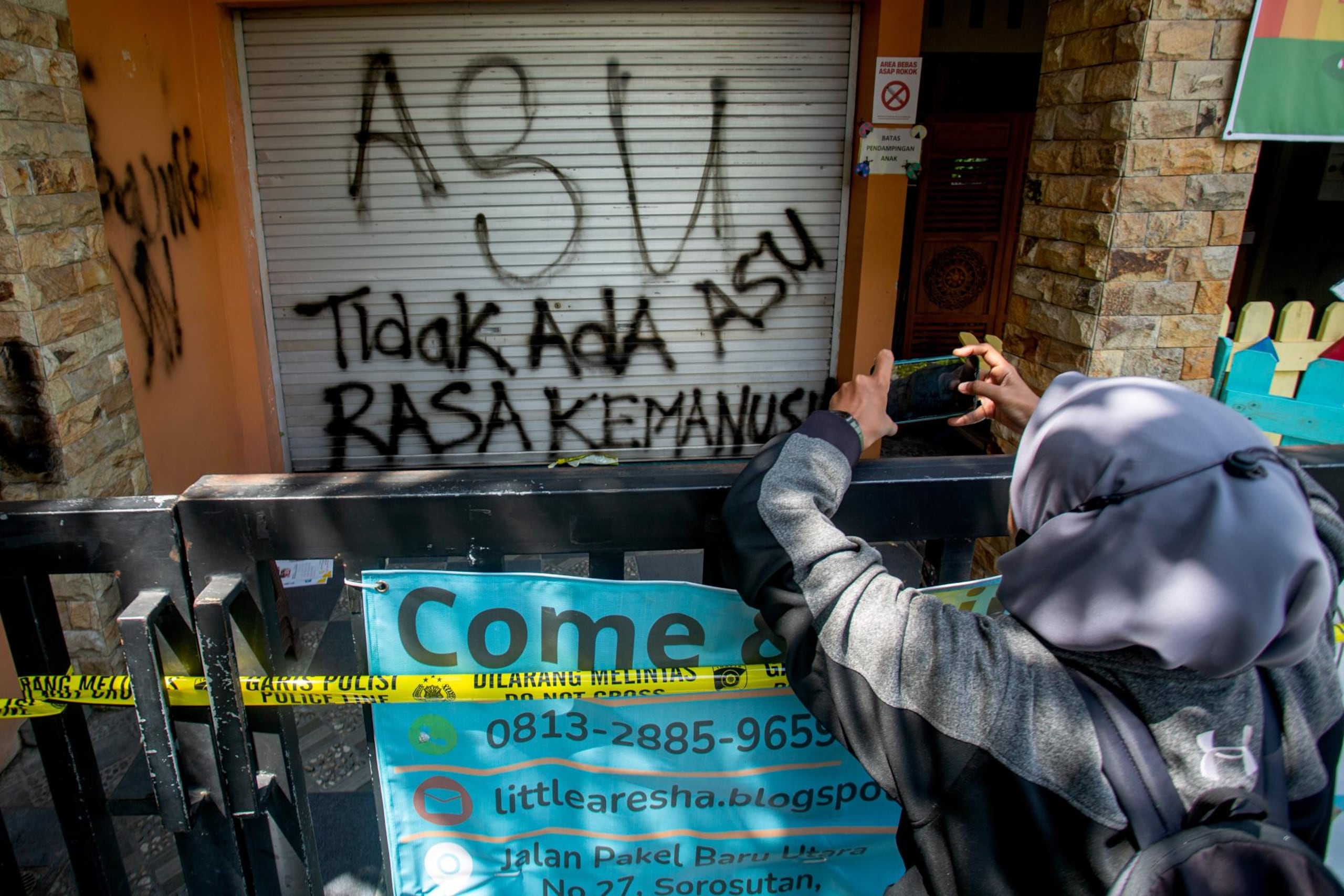 Una mujer toma fotografías del centro de cuidado infantil Little Aresha, que permanece cerrado, en Yogyakarta, Indonesia, el 28 de abril de 2026.