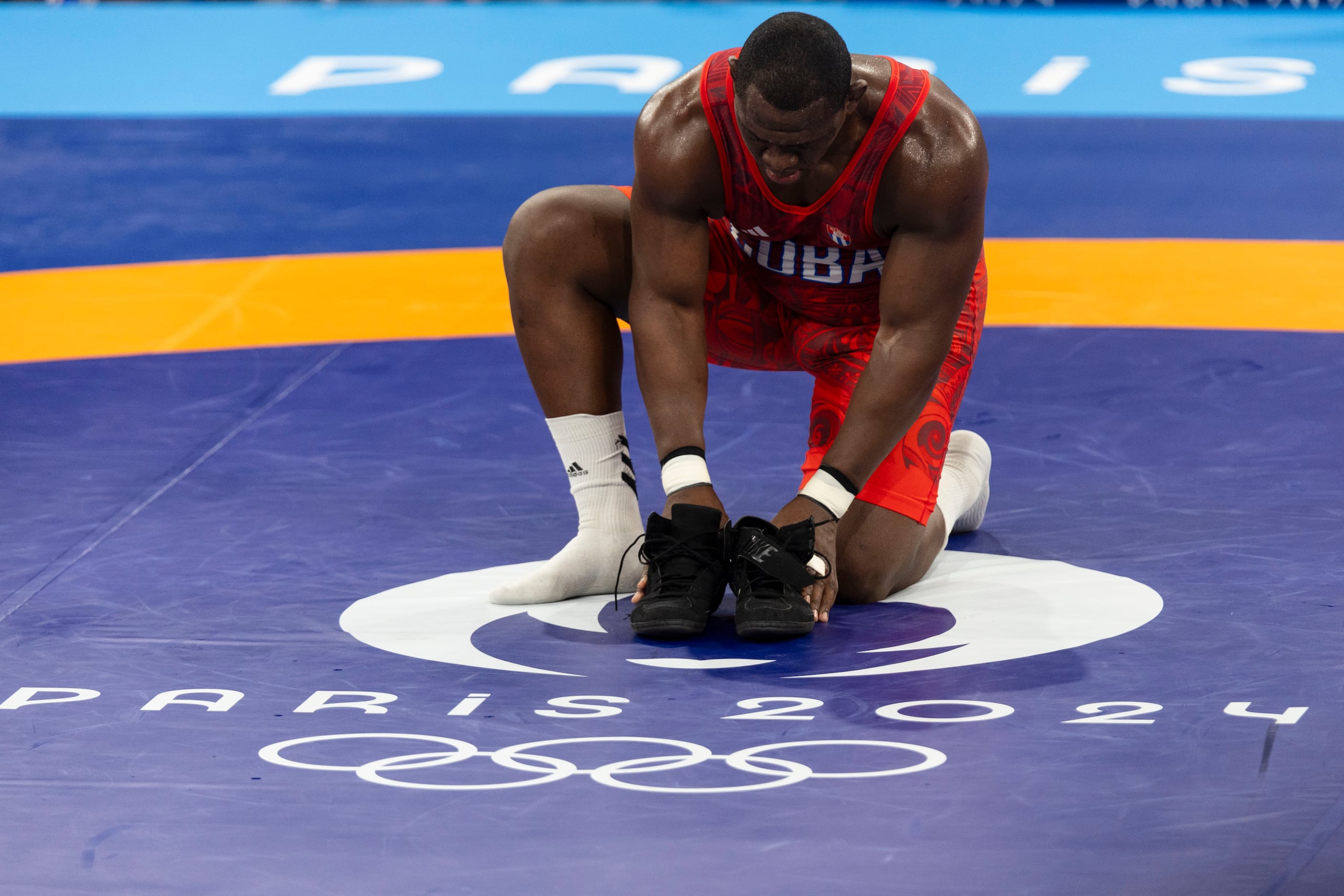 El luchador cubano Mijaín López deja sus zapatillas al centro del matre de competencia al final de su combate. Acaba de ganar su histórica quinta medalla de oro, esto en sus sextos Juegos Olímpicos, y con el logro anunció el cierre de su carrera.