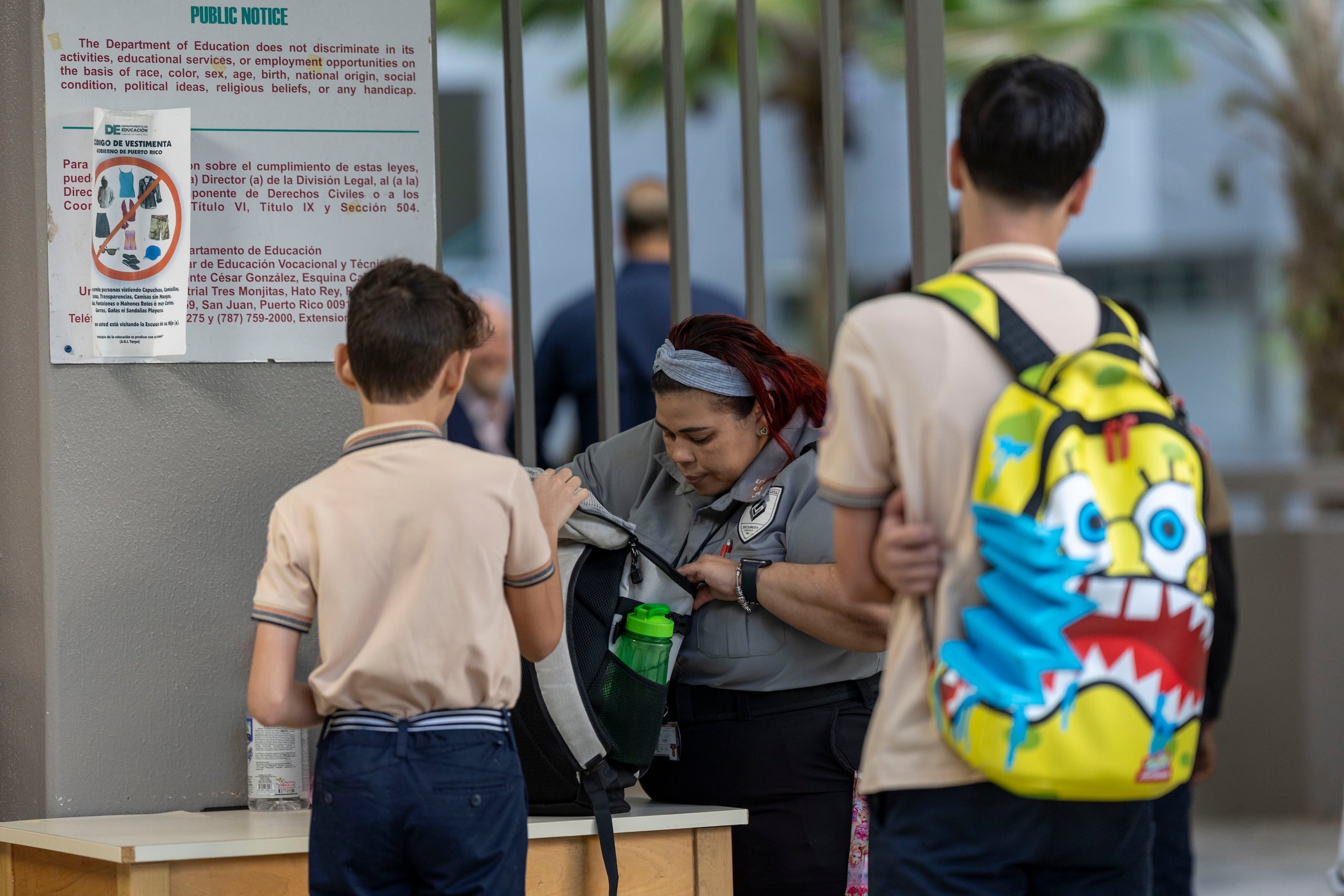 Personal de seguridad de una escuela verifica los bultos de los estudiantes antes de entrar. (Archivo / GFR Media)