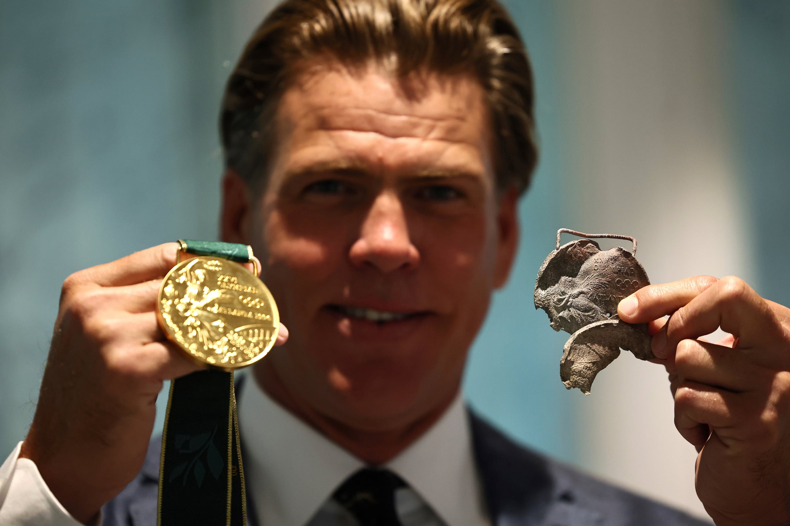 El nadador estadounidense Gary Hall Jr. sostiene una medalla original de los Juegos Olímpicos de Atlanta 1996 y que se derritió durante los incendios forestales en Los Ángeles.