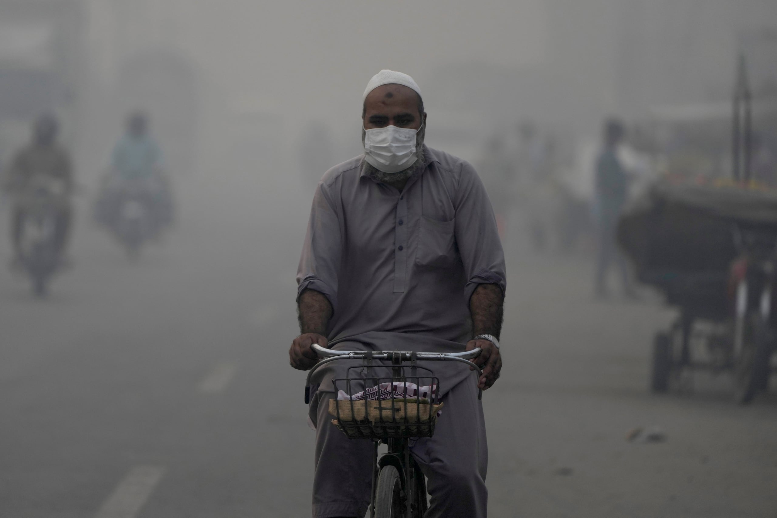 Un ciclista con mascarilla se dirige a su lugar de trabajo en medio del smog en Lahore, Pakistán.