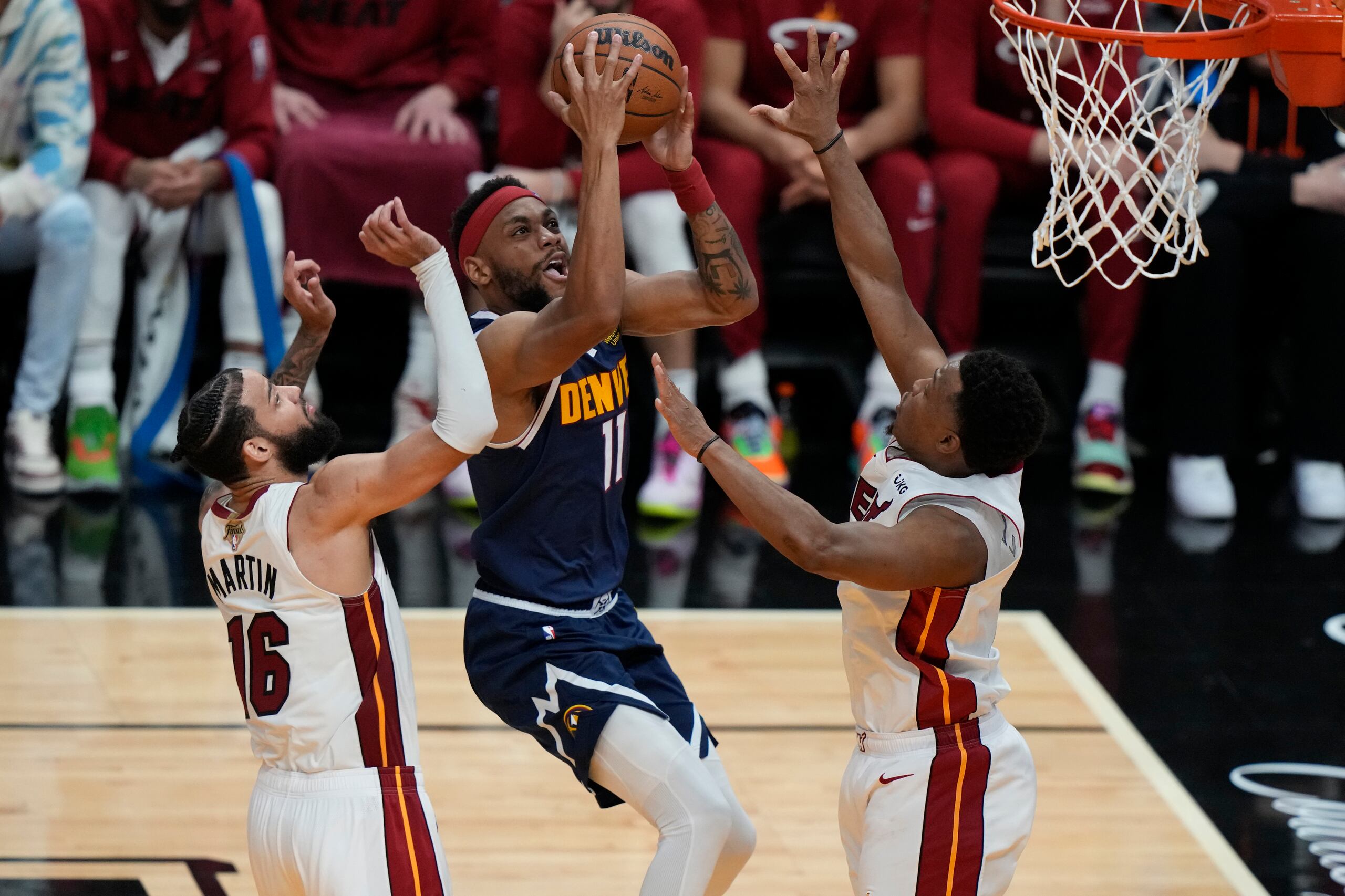 El alero de los Nuggets de Denver, Bruce Brown, avanza hacia la canasta mientras lo defienden el alero Caleb Martin y el base Kyle Lowry del Heat de Miami en el juego 4 de la final.
