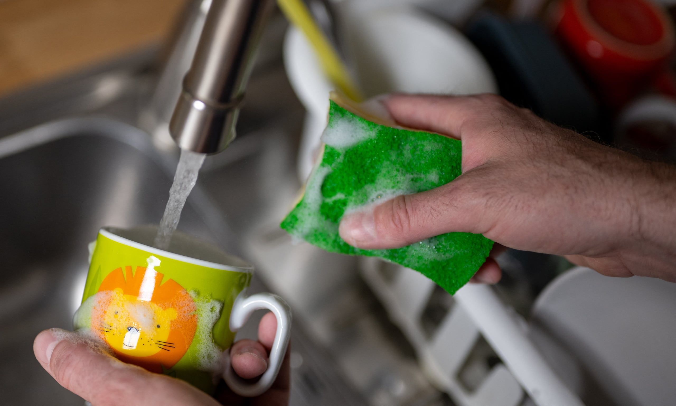 PRODUCTION - 15 April 2024, Berlin: A cup is washed with a kitchen sponge and washing-up liquid under running water from a kitchen tap. Photo: Monika Skolimowska/dpa (Photo by Monika Skolimowska / dpa Picture-Alliance via AFP)